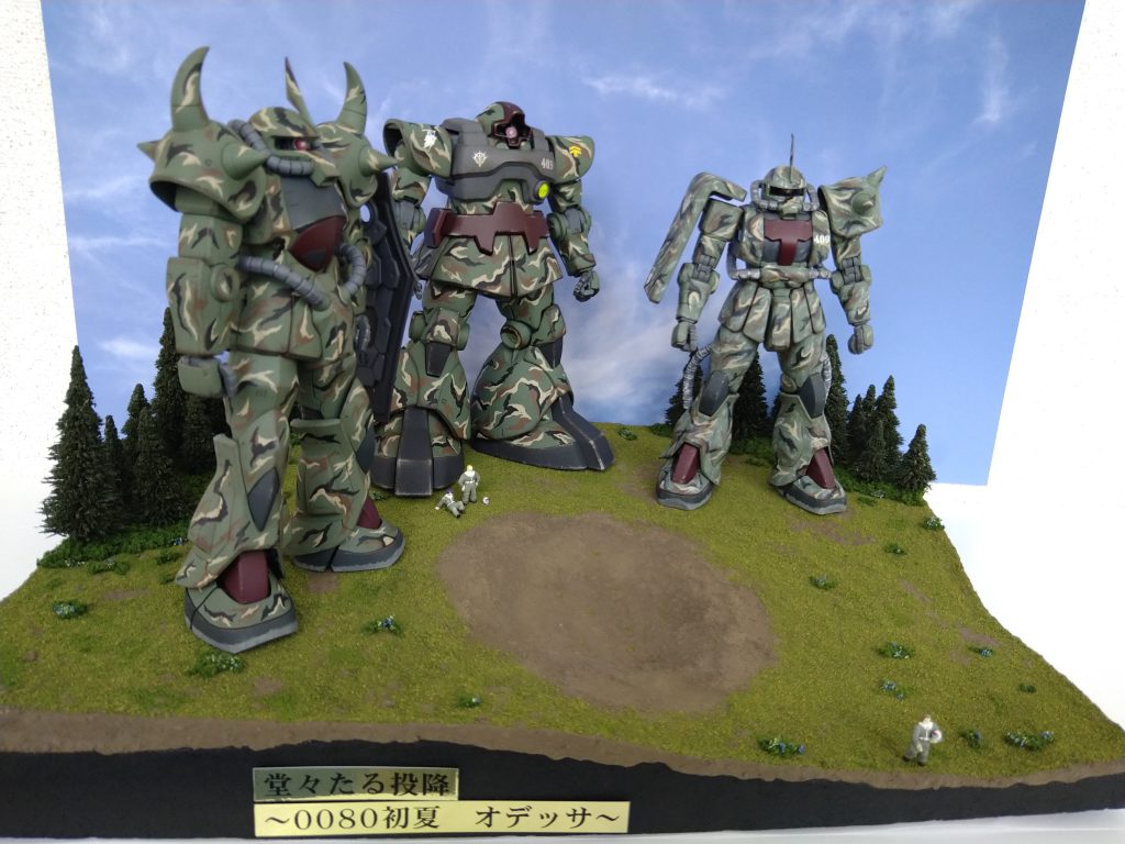 全景上から。人、小っさ‼️MGを3体も乗せるとジオラマのベースはとんでもないデカさになり、人の小ささがさらに際立ちます。撮影にはかなり悩まされました😵💫当初プランでは、ルトガーさんが握手する連邦兵と連邦車もベースに乗せる予定でしたが、あまりにキツキツだったのと、握手の対象がどういう姿なのかは想像で良い気がしたので、この構図としました。場面としては、抵抗拠点のある森を抜け、花咲く穏やかな野原でMSを降り、隊長が代表して連邦と投降の協議を行う、というものです。野原は単調にならない様、砲弾の弾着跡で変化をつけたり、草の色を変えたり、岩部分には草を生やさなかったり、といった表現をしています。全景だと細かくて見えないんですが🥲