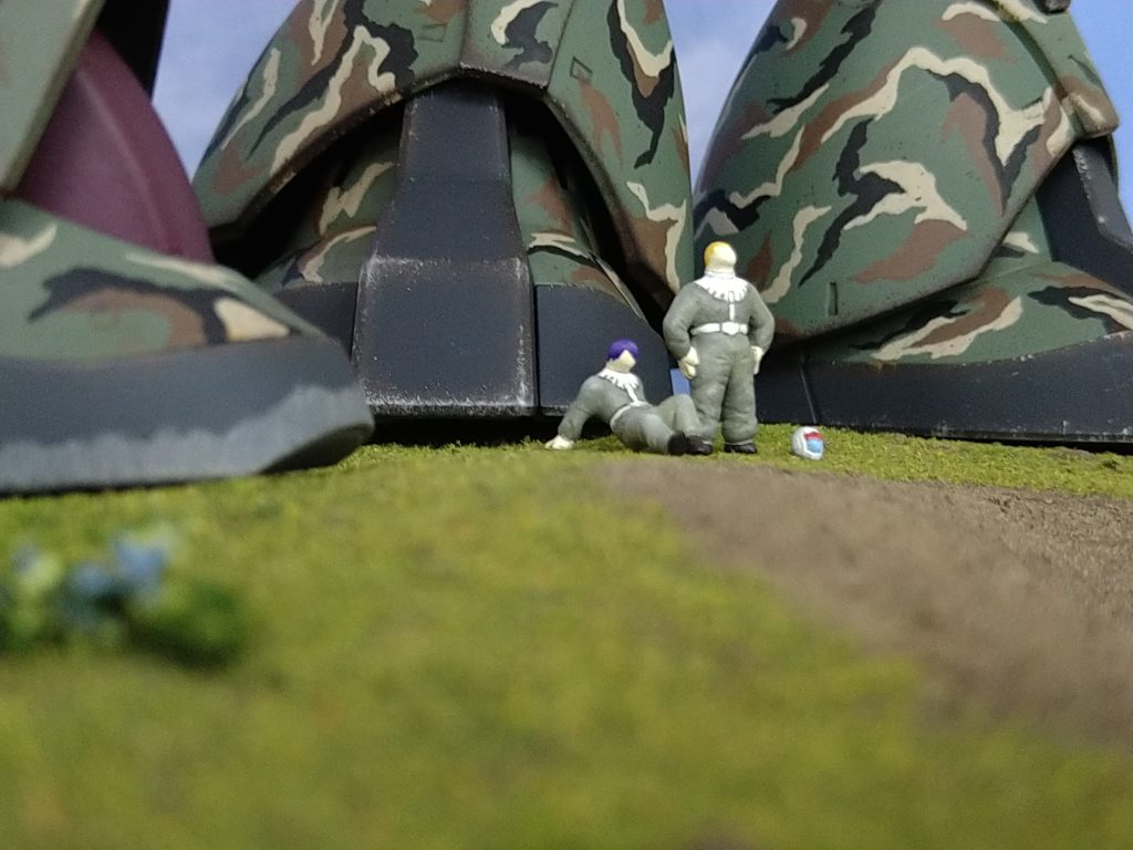 主役以外のお二人さん。『終わったなぁ。。』『。。ッスね』って感じに隊長を見守ってます。パイロットの髪型や髪の色には割と気を配り、アニメっぽい雰囲気作りを意識しました。また設定したキャラに似合うポーズを検討、表現してみたのですが、割と人物描写も上手くいったのではないかと😊ちなみにパイロット達は、エポキシパテの塊からナイフと電気リューターでイチから彫刻しました。当初は既製品の1/100フィギュアを『切った貼った』するつもりでしたが、どうにもしっくり来ず、泣く泣く決断しました🥲でも彫ってみると意外にも面白く、木彫りの仏像とかを作る人の気持ちが少し分かった様な。造形上のこだわりですが、パイロットスーツはWW2頃までのダブダブ感とハイウエストでミリ感と実存感アップを狙いました。あまり細くするとパテの強度も心配だったという側面もあります。強度に関していえば、指ももう少し細かく彫れたのですが、剥離しそうだったのでコワくて。また本来なら腕や足の側面に白いラインを入れる必要がありましたが、ミリ感が薄れるし邪魔な感じがしたのでオミットしてます。(決して、面倒だったからではありません😁)それにしても。。。今までキットに付属するパイロットを塗った事すらなかった私が、こんな事をする様になるとは。パイロットの指を(一応)5本表現できた時などは、ちょっと感動しました😁