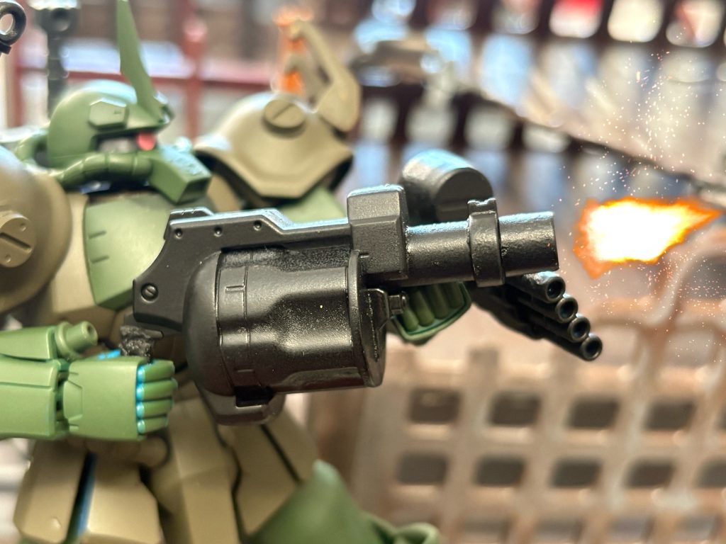 試作グレネードランチャー。B2型の設計を考案する前に各戦線のパイロットから得た意見の中に通常のグフでは敵施設や艦船に対し有効な射撃兵装が無いという指摘があった。実際、北米戦線ではこの問題を解決する為にジャイアント・バズの装備が検討されておりキャリフォルニアベースでは「グフ複合試験型」にてジャイアント・バズを装備させている。しかしバズーカ式の大型武装では取り回しが悪い事から、機動性の低下を危惧し本機ではマシンガンと同サイズで使用出来るグレネードランチャーの装備を決定。射程、精密性ともにバズーカ式に劣るが取り回しの良さを優先させている。