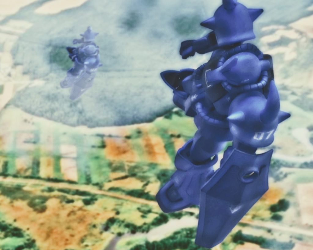 「降下っ!」リンドヴルム隊のグフ4機、ザクⅡ2機は空中でそれぞれドダイから離れて行く。離れる時はドダイがバランスを崩さない様に、MSは後ろに倒れる形になる。ジャンプするように跳ねるとドダイにも反動が伝わり最悪墜落しかねないからだ。彼らはそれを心得、可能な限り丁寧な離脱をした。離れてからMSは直ぐ様、姿勢を整える。リンドヴルム隊のMSには降下用パラシュート等はなく、ドダイに限界まで降下してもらいMS自身のスラスターで軟着陸をする。その時、自由落下により身体が宙に浮いたように軽くなるが、その反面重力に逆らうスラスター噴射時は途轍もないGがパイロットを襲う。各員は高度計に集中しながらその時を待つ。