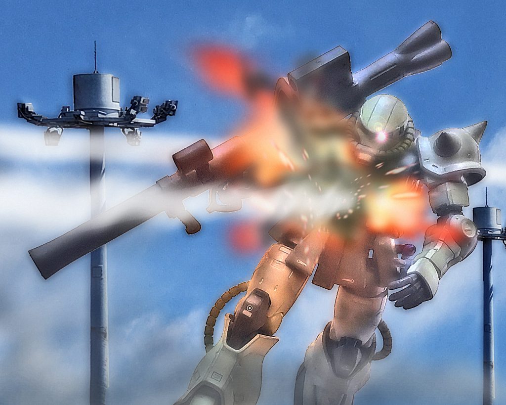 「…ウ、ウワァァッッ!?」後方にいたザクの胴体に敵の攻撃が直撃する。グフよりも基地中心部から離れ、敵部隊とは距離があった筈だ。だがザクは前面からの攻撃によりコクピットがやられている。「クローバー5がやられましたっ!?」「何だとっ!?」同じ後方にいた、もう1機のザクからビリーに通信が入る。ビリーは機体を後ろに向けると、前のめりに倒れるザクが視界に入った。そしてザクは大きく爆発すると黒煙と炎に包まれる。しかし直撃を受けた時点で中のパイロットは即死だったであろう。「クッ、別働隊がいたかっ!?」グフとザクでは機動力に差があり、ザクの動きにグフを合わせると、グフの機動性が発揮できなくなる為、別行動を取らせていた。しかしそれが仇となりザクが犠牲になってしまう。