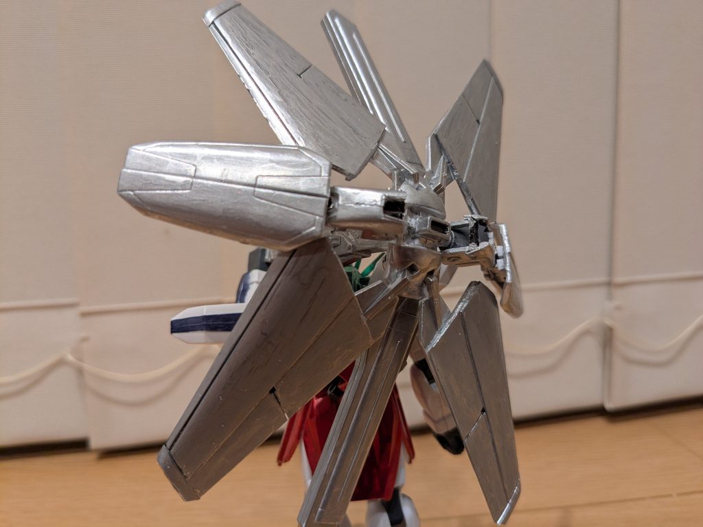 バックショット。傘さしてると完全に傘しか見えませんが笑ディバイダーのバーニア部分を稼働域ごと切除し、シールド部分との位置を入れ替えて組み合わせ、角度を調整できるようにしました。これで傘の丸みをイメージしてみました。ディバイダー中央のシールド部分は銃口剥き出しで接着し、固定してあります。それでも中央の羽部分は稼働するので、そこにアーバレストの緊急離脱ブースターのウイングパーツを加工して接着。覆えるスペースが大きくなって傘っぽくなったかな。あとはスペースが広かった上下に、ポリキャップを接着して本機のプロペラントタンクを接続し、隙間をできるだけ埋めた感じです。色は全部シルバーで塗装。シャインシルバーにしたかったのですが、途中で塗料がきれてしまい…致し方ない笑