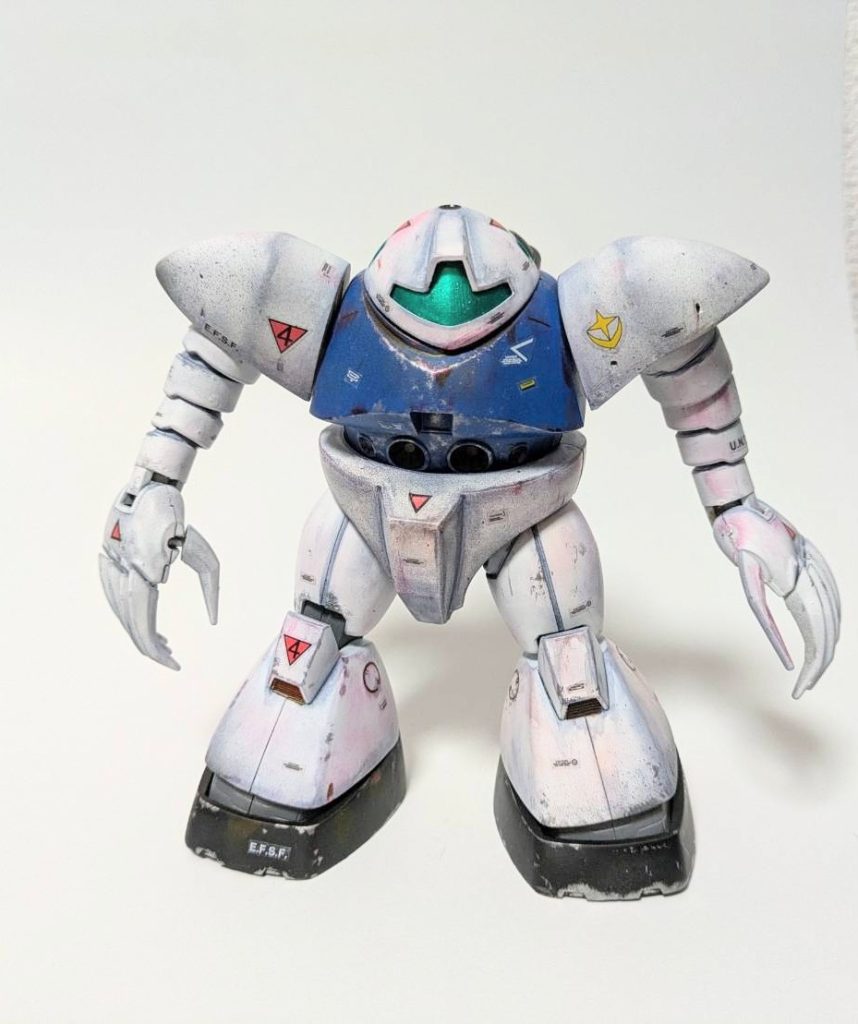 2. 主な改修点モノアイレールの廃止とバイザー型センサーへの改装ジオン軍の象徴ともいえるモノアイレールを完全撤去し、連邦軍標準のバイザー型センサーを搭載。これにより、視野の広さと情報処理能力が向上し、ジムと同等の戦闘情報リンクが可能となった。また、敵兵から見たときの「連邦軍仕様機体らしさ」を強調する目的もある。内部構造の地球連邦規格化操作系を連邦軍の標準仕様に改修し、連邦軍パイロットが短期間で訓練可能にした。装甲と外装の再塗装機体全体を青と白の塗装で仕上げ、連邦軍の海洋部隊仕様に統一。さらに、装甲表面に反射コーティングを施し、敵機からのビーム攻撃を軽減。. 連邦軍の運用と戦術的役割ブルースターゴッグは、連邦軍の水陸両用作戦の新たな主力機として、戦後の残党狩りや海上封鎖任務に投入された。その特異な性能と改修による操作性の向上により、以下のような任務で活躍した:沿岸部での敵潜水艦制圧作戦密林地帯のゲリラ掃討作戦(河川や湿地帯での優れた機動性を活かした運用)特殊部隊の支援機としての運用