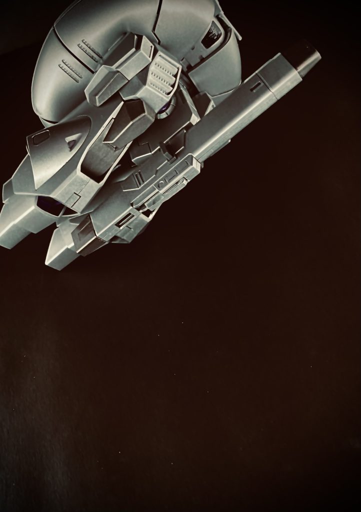 「釈放だ。出ろ」　次の日の深夜。牢に入れられている私達をまるで動物か何かを見るような目で見ながら、格子の向こうで年若い青年兵が言う。「あなた達っ！所属名、部隊名、上司の名前。…あなたの名前もいいなさい。報告書に書かせて貰うわ！」　後ろで、よせ。とモールダーが言う。「私達は、地球連邦捜査官なのよ。あなた達に私達の捜査を邪魔する権限は無いわ！」　これだけ言っても、目の前の兵士はどこ吹く風だ。…丸一日も拘束されたのよ。「…もう行こう。スカーリ」　モールダーが肩に手を置く。…でも、そう言おうとモールダーを見る。彼は何かを言いたそうな顔を横に振ると、行ってしまう。「ちょっと、モールダー？」　言いたいことは分かるよ。スカーリ。そう言ってさっさと車に乗ってしまう。納得のいかないまま、助手席に座る私にモールダーは言う。「…彼等、ティターンズじゃ無いよ。…いや、軍ですらないかも知れない」　…そう言って、車を発進させる。〜数分前〜　…釈放だ。と言う声に、すぐさま女性の声が反論する。「彼」の相方だという女性だろう。なかなか優秀な捜査官らしい。モールダーとスカーリが拘束されていた牢がある通路の角、その陰の壁に、男は背を預けている。軍の施設内にはそぐわない、きっちりとスーツを着た初老の男だ。兵と女性のやり取りを聞いていた男は、ゆっくりと、懐から今ではもう珍しい紙パッケージのタバコを取り出すと、口に咥え火をつける。…モールダー達のやり取りを満足そうに聞いていた男は、笑みを浮かべると、まだ半分も残っているタバコを灰皿へ押し付ける、そして静かに薄暗い施設の奥へ歩いて行く。…コツコツと足音を残して。「ちょっとモールダー。軍ですらない。ってどう言うこと」「…奴がいた。…肺ガン男。……僕には分かる」