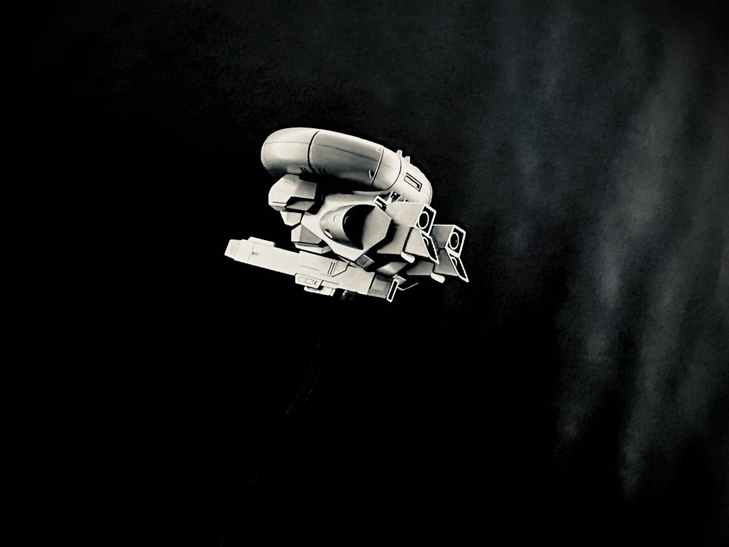 資料　目撃証言　あの晩のことは覚えているよぅ、…そうだねえ、五人、六人だったかな、ああ、アンドレが居たから六人だねえ。…アンドレ？ああ、ウチの常連さあ。みんないい感じに酒が回ってたと思うよ、あっ、酒の所為だ。って言うつもりはないよう、神に誓ってね。だってみんな見たんだもの。酔いだって一気に冷めちまったんだからね。…常連の一人がさ、真っ青な顔で店に飛び込んで来たんだ。大変だって、で空がだの、空にだの言うからさ、オーナーが様子を見に行ったんだ。そしたらオーナーも青い顔でカメラだ、カメラだって奥にいっちまったんで、みんなで外に出てみたのさ。あたしらみんなお祭り騒ぎが好きだからね。だってさ、気になるだろう、大の大人が二人も青い顔してさぁ。…そしたらさぁ、あそこ(北の空を指差す)、あそこにさ、浮いてたんだよ。こう、銀色のがさ、ふわふわって(手をヒラヒラさせる)、…え、飛んでた。じゃなく？…違う、違う、こう、ふわふわって、風船みたいにさ。だってあたし、近所のセールの風船だと思ったもの。でもあれは風船なんかじゃあないね。銀色のキラキラした光り方じゃないもの、なんか金属の光り方だもの、うまく言えないけどさ。…え、一人で見たか？って、みんないたよう、みんなで見たんだよう。アンドレなんかさ、図体のわりにポカーンって口あけてさ、フフッ。オーナーなんて、夢中で写真撮ってるしさ、…写真？それなら店の中に貼ってあるよ。オーナー沢山撮ってたからさ。…他に変わったことは無かったかって？うーん、そうね、あっ！そうそう、最近店に来るようになったお客さんでさ、元軍人って人がいるんだけどさ。ほら、ずっと北の方に基地があるだろ、そこの人だったんじゃないかってみんな言ってるんだけどさ。…え、その時一緒だったかって、いたよう、いたいた。その元軍人さんがさ、…え、名前？知らないよう。その元軍人さんがね、言うんだよ。あれを見上げながらさ、ブツブツとさ、「俺は知らない」って。しばらく言ってたげど、急に頭を抱えてさ、知らないんだ。って叫んでどっかいっちまったよ。…あれから見てないねえ。…気にならなかったかって？それどころじゃなかったよ。だってあれがさ、こう、浮いてたと思ったらさ、急に上にいったり、下にいったりってさ(手のひらを上下に動かす)、何回かさ、行ったり来たりしたと思ったらさ、ビューっていっちまったんだ。…うん、ビューってさ(北の空を指差す)。添付された写真はその時オーナーによって撮影されたもの