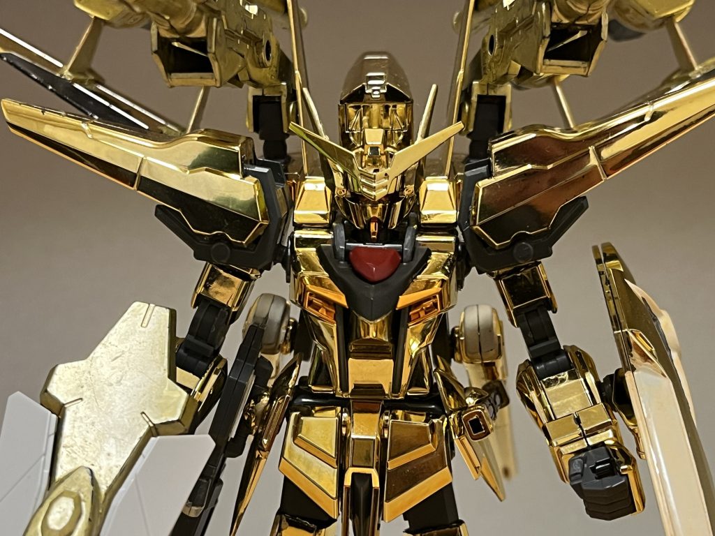 性能外観こそアカツキ本体と変わらないものの、実際には大改修が施されており、性能面は大幅に強化されている。動力源ハイパーデュートリオンエンジンへと交換されており、無限に近い稼働時間と高出力を実現している。機動力･スピードエンジン出力向上とスラスター強化によって、大気圏内での単独飛行を可能としている。さらに背部バックパック「ホムラ」によって、オオワシ以上の機動力を誇り、その気になれば亜光速レベルまで加速可能(ただし、相応の負担がパイロットにも掛かる)。攻撃能力両腕と両脚には高エネルギー収束機器の搭載しており、武器を持たずとも高い攻撃力を誇る。これは、後述するヤタノカガミとVTP装甲の併用によって可能となったもの。さらに後述する武装面も、従来のアカツキ以上に豊富となっている。防御力・耐久性以下2種類を複合した特殊装甲となっており、絶大なビーム耐性のみならず、実体兵器にも高い防御力を手に入れている。ヤタノカガミ全身の黄金に輝く鏡面装甲。ビームを屈折・反射する特徴を持ち、敵の放ったビームを機体の表面で受け止め、相手にそのまま跳ね返す、あるいはそのビームを別の敵機に当てるという芸当も可能とする。反射出来るビームの上限が極めて広く、通常のビームライフルはもちろん、ガナーザクウォーリアが持ちうる高出力のオルトロスすら反射できるほどで、果ては戦艦に搭載された主砲や陽電子砲までも無効化できるほどであり、ビーム兵器に対してほぼ無敵の強さを持つ(跳ね返し切れない陽電気などの高出力ビームは拡散に止まっているが、それでも規格外の防御力)。極めつけは、本機にとってギリギリ(ヤタノカガミが赤熱化・熔解する)とは言え、戦略兵器レクイエムのビームですら反射してしまう。ヴァリアブルトランスフェイズ装甲VPS装甲(ヴァリアブルフェイズシフト)とTP装甲(トランスフェイズ)の長所をそれぞれ組み合わせた特殊装甲であり、本機では関節部を含めた全箇所に施されており、さらには全身のヤタノカガミと組み合わせる事にも成功している。略称は、VTP装甲。TP装甲のように「被弾時にのみ反応し、被弾箇所周辺にのみフェイズシフトする」仕組みであり、エネルギー消費を大幅に軽減する事に成功している他、VPS装甲のように「流す電流の量を変化させる」事で省エネルギー化だけでなく、逆に強度を上げる事でTP装甲の「実弾防御力が従来のPS装甲に若干劣る」という欠点を解消している。本装甲によって、ヤタノカガミの「実体兵器に弱い」という欠点をカバーしており、機関砲やミサイルのみならず、レールガンにも難なく耐えられる。弱点について上記のように、ビームと実体兵器の両方に対して、驚異的な防御力を実現しているが、実はこれでも少なからず弱点が存在する。まず、ヤタノカガミは施されていない関節部は、ビーム兵器によって破壊できる(それでも関節部にもVTP装甲が施されている為、実体兵器でも破壊は難しい)。次に、対ビーム装甲に滅法強い対艦刀、加えて磁場によりビームを形成するビームサーベルに対しても、一撃であれば両断こそしないが本装甲にはダメージが確実に入ってしまい、これが数撃以上となれば両断可能となってしまう。特にビーム刃を併用するタイプの実体兵器や対艦刀に対しては、通常装甲と大差ない防御力しか持たない為、一撃で撃破されかねない。