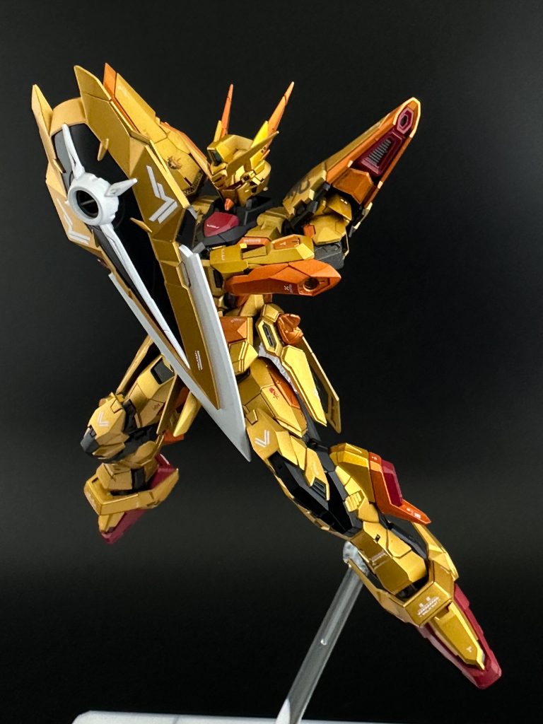 色レシピ本体メインゴールド:ガイア黒サフ→ガイアスターブライトゴールド手首など一部は上からタミヤクリアイエロー、オレンジ部分はクレオスGXクリアオレンジを重ねています。フレーム部ガンメタ:ガイアガンメタサフ台座はマスキングで赤のクロスを塗ったあと、裏面からホワイトを入れています。また、今回は全体のフィニッシュをガイアセミグロスクリアーで半光沢に仕上げました。白:ガイアグレーサフ→ガイア白サフ外装など黒:ガイアガンメタサフ→クレオス黒鉄色赤:ガイアピンクサフ→ガイアブラッドレッド