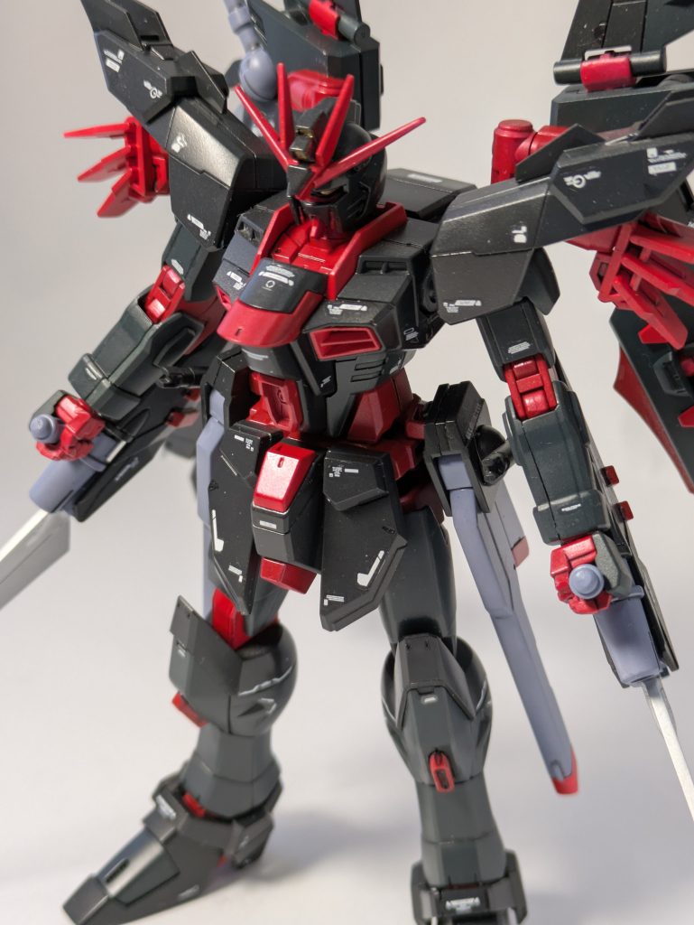 カラーリングは同じノワールストライカー装備の機体のアストレイノワールをイメージしてフレームを赤、装甲を黒とダークグレーで塗り分けたのですが、全体に真っ黒になってしまったので、全身に白いデカールでアクセントを付けました。