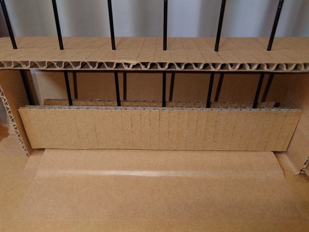 持ち手棒の保持は、折り曲げたダンボールのところにキリで穴を開けて(3cm間隔)、下の方はダンボールを重ねて持ち手棒ベースと同じ仕組みにしました。