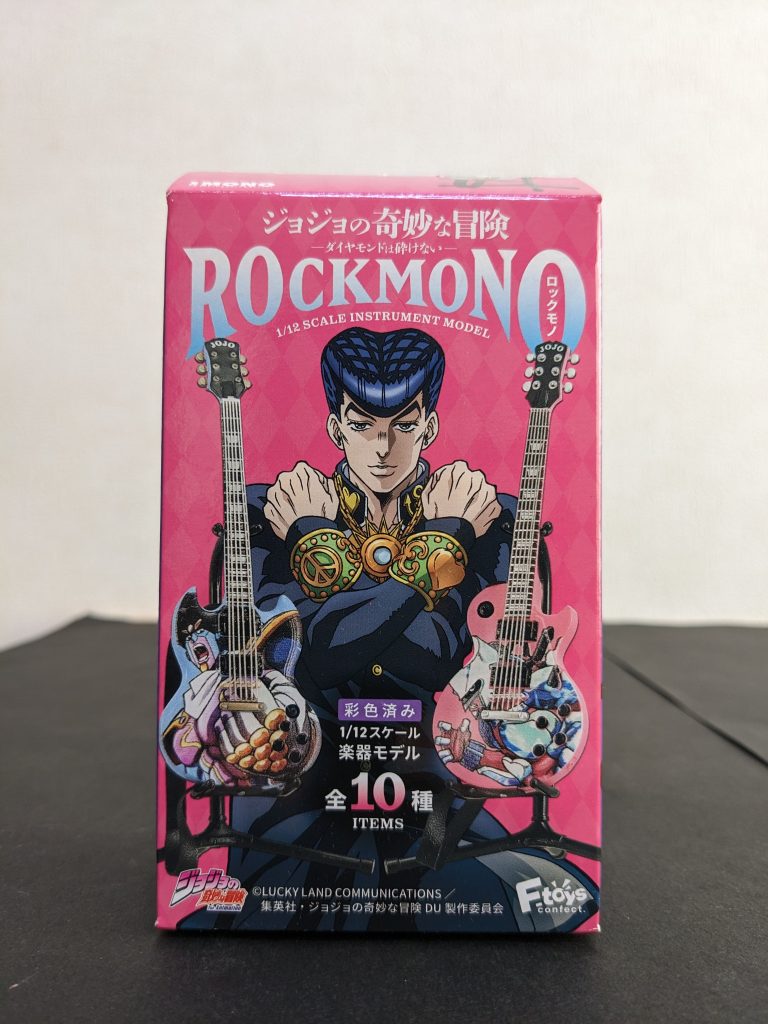 ギターはこのシリーズでゲット👍‼️今日、食料品の買い出し(我が家では、コレは自分の分担なのです💦)に近所のスーパーに行き、前の弾もソコで買えたので、「アーティファクトあるかな〜❓」と微かな望みをかけて食玩コーナー覗いてみたら、ソッコー品切れしたのか未入荷なのか、影も形もなし😅その代わり❓にこの箱見つけて、「この大きさ、もしかしたら、ウチのジークアクスにジャストフィットでは🤔❓」と思い、一つ買ってみた。何入ってるかわからん全10種のうち、ベースも3つあるので「ギターが出ますように🙏‼️」と念を込めて開封したら、見事コイツをゲット👍‼️7弦はもちろん😅どのみちSCHECTERのドロリスモデルとドンピシャの色(黒＋金)、形(ムスタングシェイプ)はライナップに無い中、レスポールやSGよりはストラトキャスターの方がまだホンモノに近いので、まぁ大当たり🎉‼️なのではないかと。サイズ感も大き過ぎず小さ過ぎずの妥当な線だと思いますし、ストラップも入ってるので、「144サイズのガンプラにギター持たせたい✊‼️」って方にはオススメのアイテムです‼️(しかし、GUNSTAユーザーの中でどれほどいるのかしらん・・・相当ニッチなニーズだな😅)