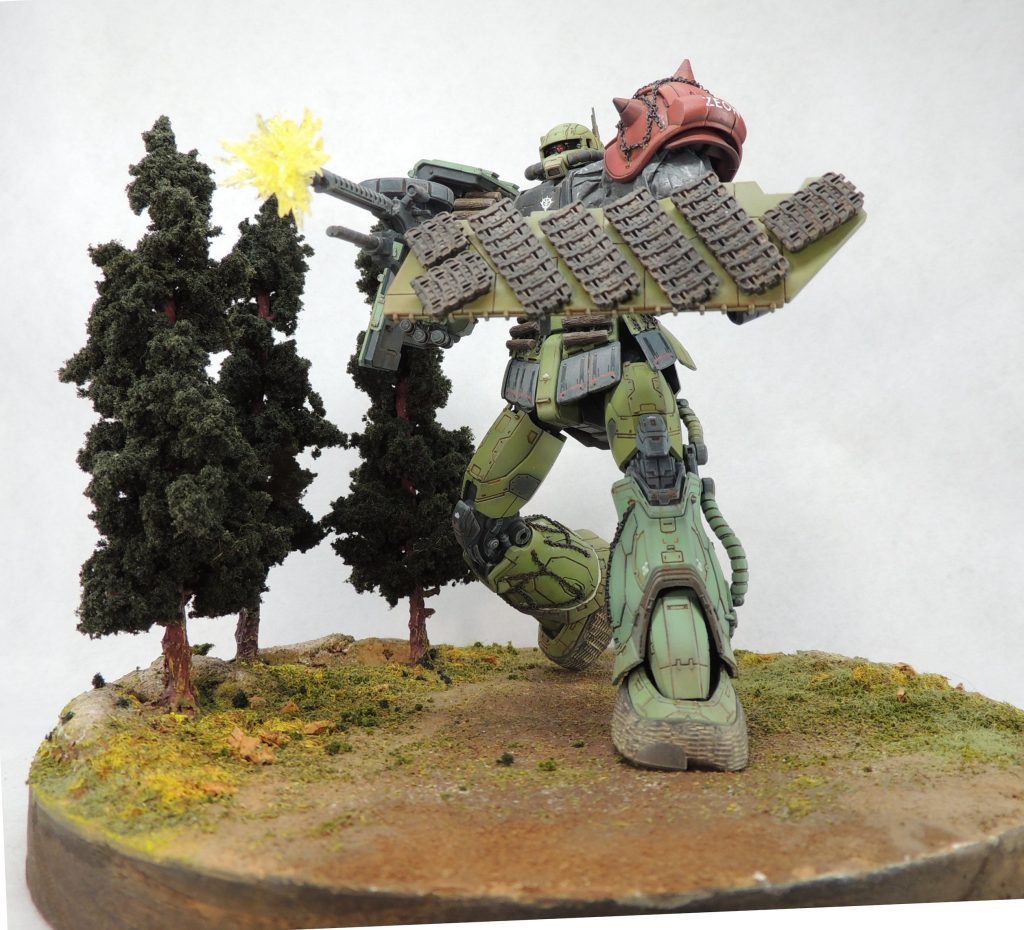 以前製作した簡易ジオラマに設置してみました。■マズルフラッシュのエフェクトパーツ:ザク・マシンガンの先端に差し込むかたちで自作しました。製作方法は簡単で、透明プラ板をニッパーで荒く切り取り、破片を瞬間接着剤と透明レジンを使用して、放射状に接着しました。クリアイエローを吹き付けて完成です。