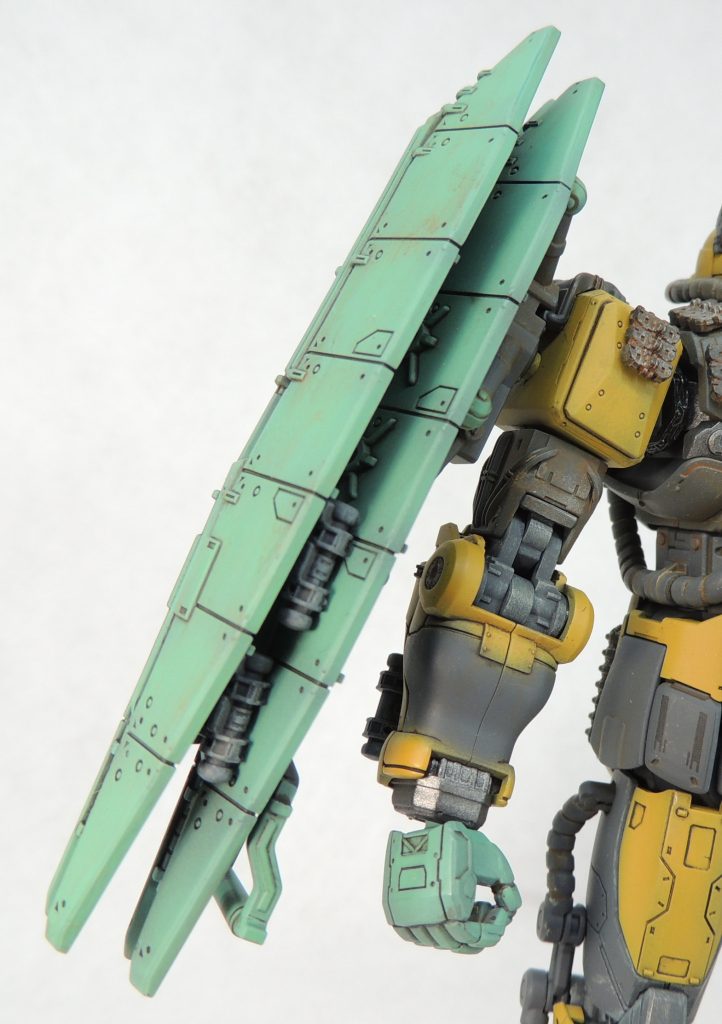 ■右腕部：組立説明書に従い、肩の側面に剥き出しのコードのディティールアップパーツを、前後に履帯パーツを接着しました。また、二の腕は外装が外れた状態の新規パーツに換装しました。手首から肘までは2色で表現。マゼラ・アタックの装甲と右手はグリーン系の塗装としました。3連装ミサイルは1.0mmΦ真鍮線で固定。