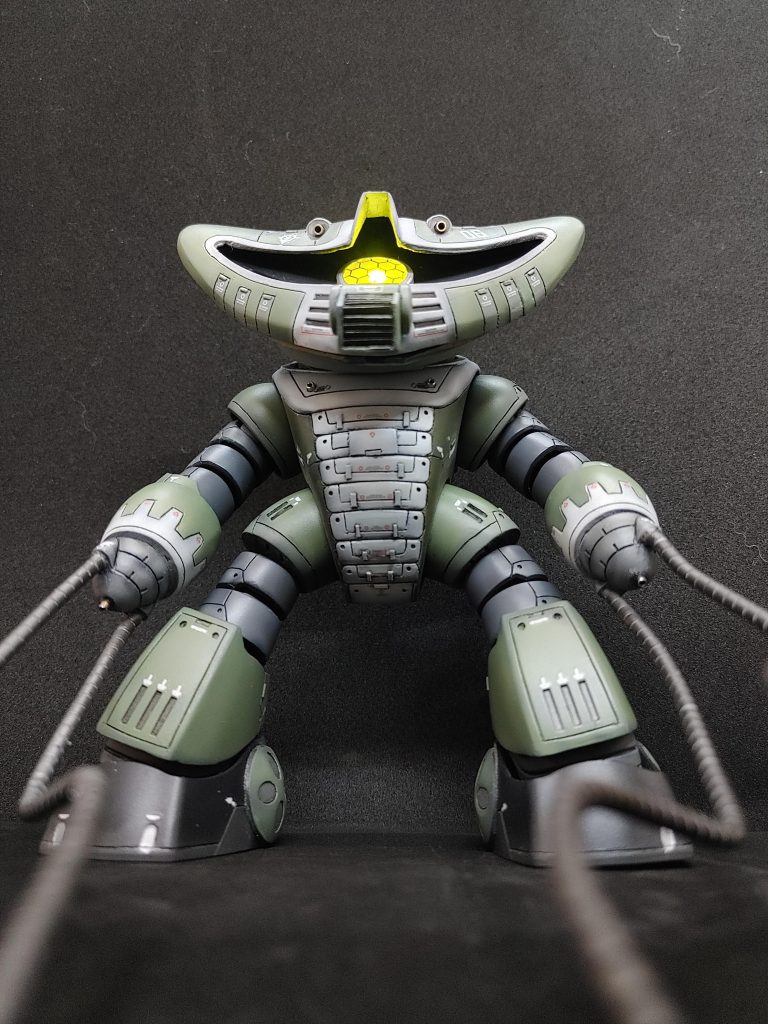 改修箇所は上からモノアイバイザーをプラ板で延長モノアイまわりをくりぬいて、プラ板でレールを作ってモノアイを可動できるようにくりぬいたモノアイをお湯マルで型をとってレジンで複製、クリア化モノアイ電飾頭が大きくて電飾スイッチ、電池が入りそうだったので頭の中におさめることに。てな訳で頭どうしようと思いマグネットで頭の前後のパーツを取り外し可能に取り外し可能にしたことにより頭パーツの合わせ目どうしよう。ということで頭前パーツのふちに1mmプラ角パイプ貼って後ろに額縁みたいにして頭後パーツのまわりを1mmくらい削って小さくして段差モールドっぽくしました。鼻？が下に伸びててエロ顔だな～ということで少し短くしました。口？はプラ板を放射状に貼ってフィンっぽくしました。首はアッガイパーツを使ったので頭、胴パーツの処理しました。アッグガイの首の蛇腹を削って胴パーツと同化させて猫背っぽく胴パーツは肩パーツ後ハメ。首、足パーツ繋ぎ関節加工肩パーツにジョイント入れてズゴック腕パーツを繋ぎました。肘関節までズゴックのモノを使用しその先をぶったぎってアッグガイの腕パーツを3mmくらい切ったものと繋ぎました。手先パーツを別パーツ化股パーツ(アッグガイ)と腿パーツ(ズゴック)繋げられるように膝関節パーツ(アッガイ)を途中で切って腿パーツと接続足パーツ(アッガイ)を内外だいたい同じ形に切削し脛部分(アッグガイ)を貼りつけ。足下パーツ(アッガイ)にくるぶしパーツ(アッグガイ)を貼りつけMSバーニア各所スジ彫り、プラ板チップメタルビーズ少々カラーリングはザクカラー、いわゆる量産機カラーに変更