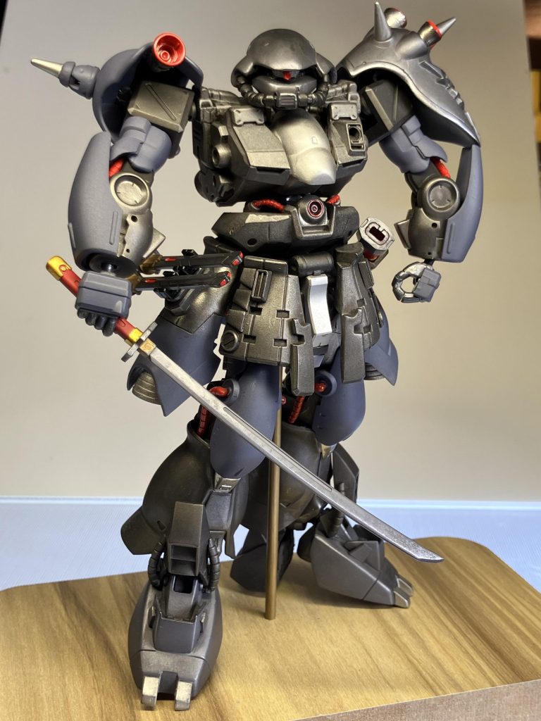 マッチョザクの完成!今回の機体コンセプトは近接戦闘を想定したもので、作者のロマンを追求した結果、武装は流用品ではあるがオリジナル塗装をした物で、HGジンハイマニューバ2型のMA-M92斬機刀を装備、火器では無く実剣を使用する事で、隠密行動をしながら熱源探知を抑え背後からの一突きで落とすスキーニングス戦闘が出来たらカッコいいなぁという妄想を形にしたもの。また、ザクにビーム兵器は御法度かもしれないが、えぇい!この際そんな些細な事はジャブローの蛇にても喰わせておけ!と言う事で、HGマスラオのGNロングビームサーベル「ハワード」、GNショートビームサーベル「ダリル」を装備、エイハブリアクター2基で稼働するかは不明だが、ザクが二刀流で敵を切り刻む様を見たいので300年前の動力源で頑張ってビーム出してくれる事を願う。また、唯一の中距離攻撃として、複数の敵に囲まれた際には、腹部に設けられた咆口からメガ粒子砲を放つよ!(作者設定)ちなみに、この腹部パーツは旧キットメリクリウスの股間パーツを逆さまにして使用。その他いろんなジャンクパーツを張り合わせて製作しています。覚えている範囲では、 ・バルバトス・マラサイ・F2ザク・ヤクトドーガ・ケンプファー・アレックス・ザクⅠスナイパー・ザク2・デザートザク・プロトタイプグフ・ジンハイマニューバ2型・マスラオeat……