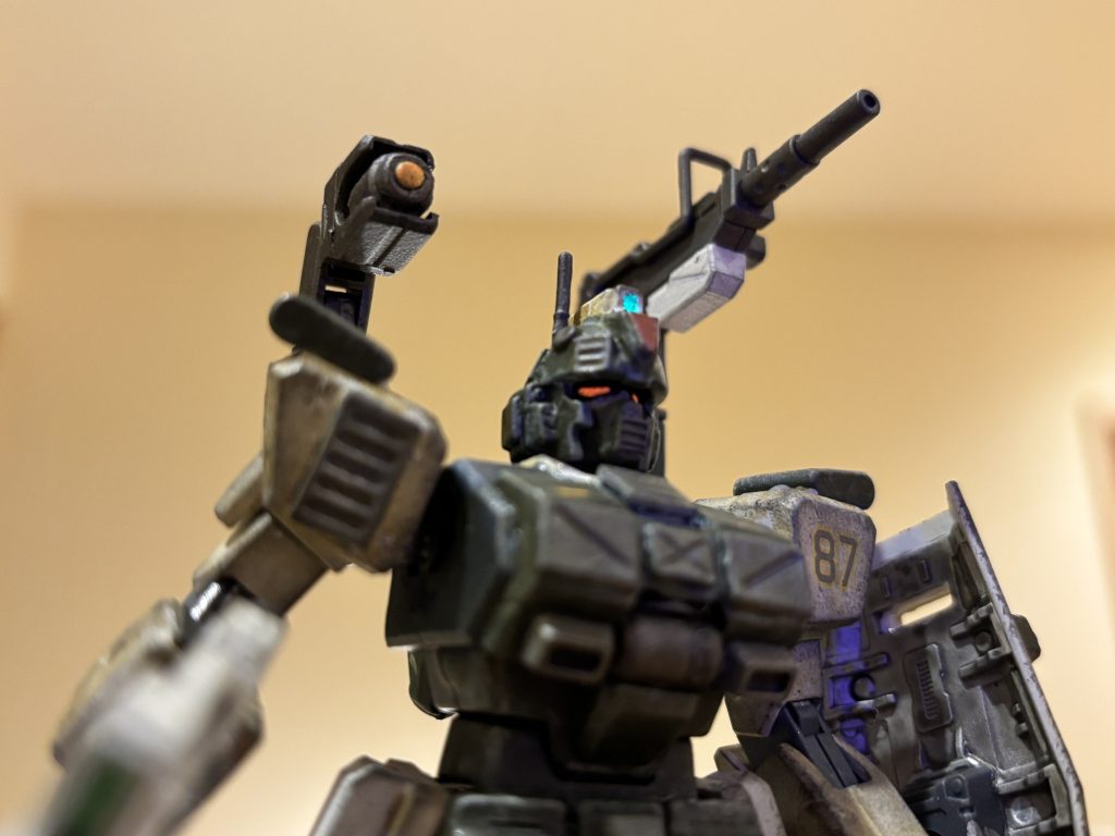 破損機からもぎ取ったマニピュレーターを、無理矢理ランドセルに移植しているのが、この機体最大の改修ポイントです。マシンガンやビームライフルを保持して、引き金を引くことだけができるように改修されています。建造物など遮蔽物の陰（上方）からの射撃も可能になったのですが、通常の射撃にしても物陰からの射撃にしても集弾率が低かったため、右側のマニピレーターには補助カメラ・センサーを設置し、集弾率の向上を図っています。