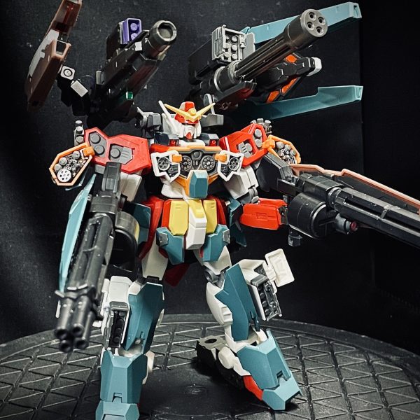 ミキシング完了したHGガンダムベビーアームズのフルバースト状態です。武装概要ビームガトリング２門：ユニコーンのシールドガトリングを拝借し、シールドとしてルブリスウル、ソーンのシールドを貼り付けビームキャノン：ルブリスソーンより拝借。バックパックにマウントガトリングガン：ルブリスウルより拝借。実弾のガトリングガンと設定して、バックパック中央にに大型ドラムマガジンを設置大型シールド兼レールガン２機：ウルとソーンのバックパックに付いているものを独自解釈。レールガン自体はトールギスが装備しているので「あるもの」として判断肩部、胸部の展開カバー裏にも兵装追加：オプションパーツ設置脚部ミサイルコンテナ追加：ジムIIIのショルダーミサイルコンテナを流用 アーマー関連下半身が華奢になるので、フロントに装甲追加、かかと部分を30mmのキャタピラを流用し、つま先たち状態にし、キャタピラでの機動イメージ。バックパックはジムIIIのバックパックと変更し、リアスカートには初期シールドをバーニア付きのオプション装備として設置 （4枚目）