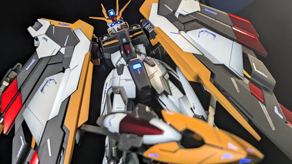 やはりこちらのマントを閉じた状態がお気に入りです。各所センサーカメラ類はメタリックマーカーで塗った後に、蛍光塗料で光らせています。カラーに関して、個人的にはF91シリーズに代表される「青」が好きです。また、デカール類も蛍光発光するものを選びました。デザインも「キャラクター感」の強いものを採用してます。小さな赤いデカールはキット付属のものを使用しています。