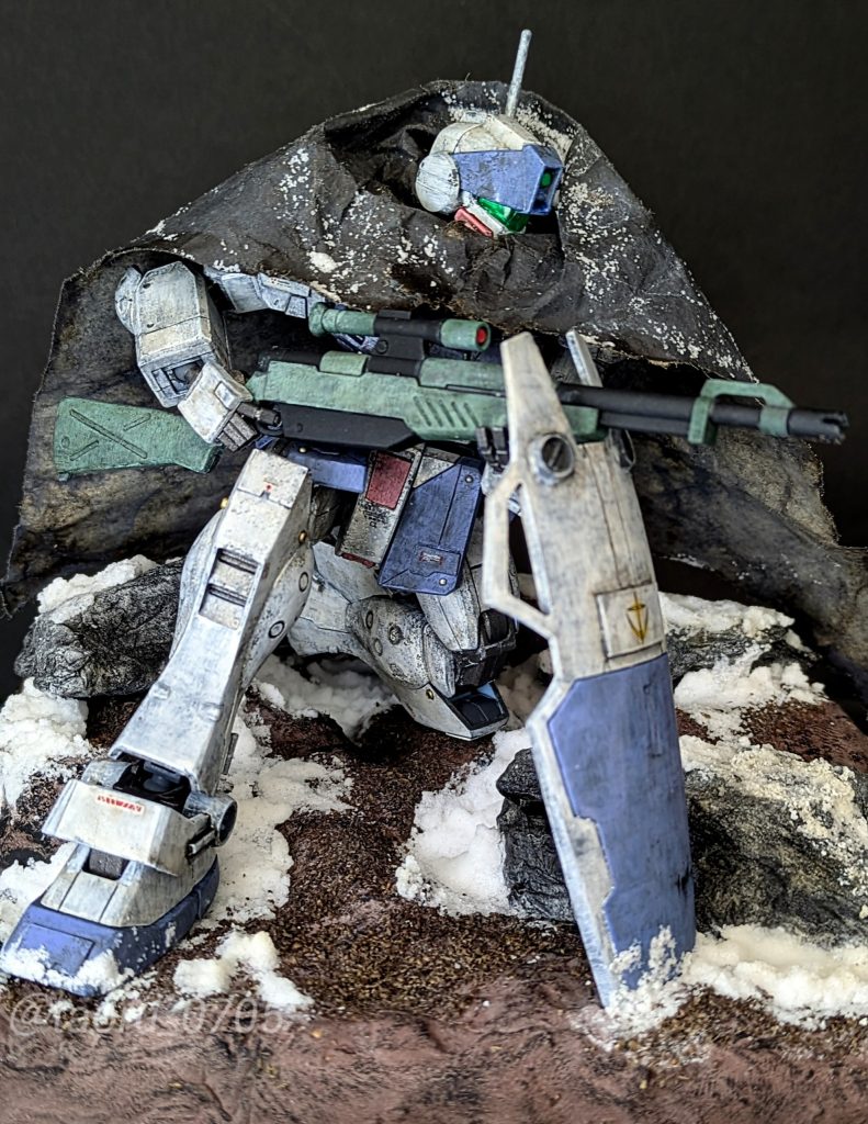 「ロボ+マント」の好みを正当化するために冬期のジオラマを構想していたのですが、マントが可動域の不足を隠してくれたおかげでカッコイイ感じの狙撃ポーズに見えるようになったのは嬉しい誤算でした(笑)段差をつけることで姿勢を真っ直ぐにする効果は狙っていましたが、良い相乗効果になったと思います。キット本体の改造だけではなく、飾る環境で補う方法もあるのだと、実践してみて勉強になりました。