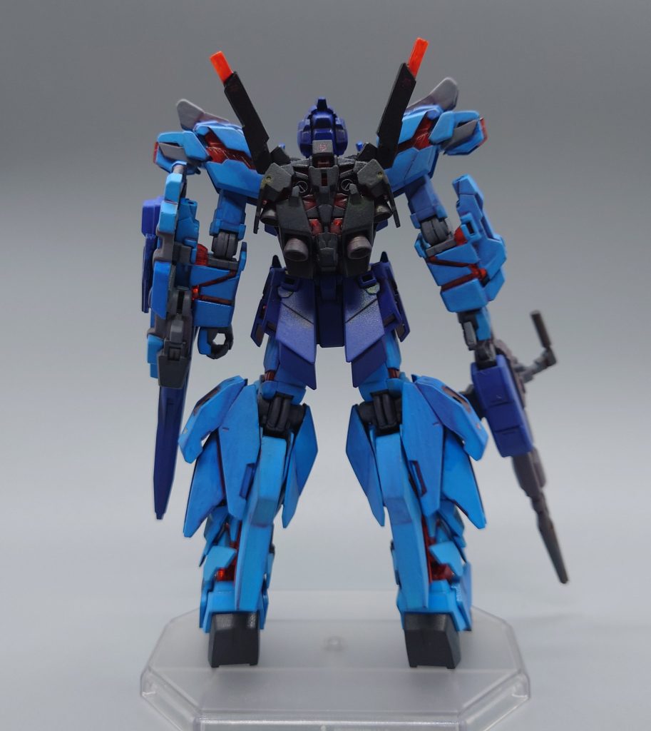 武装やホバーユニットのテストに加え、戦闘支援システムとの親和性を測る実験が行われていたものの、本採用となるNT-Dは別機体により別チームが制作中だった事、及びセキュリティクリアランスの関係上搭載不可能であった。そこで本機は代用として「ES-E( EXAMシステムエミュレータ)」なるシステムを搭載する運びとなった。コックピット前面に外付けされたES-Eを起動した瞬間、フレームが赤く輝き…ブルーは暴走を初める…