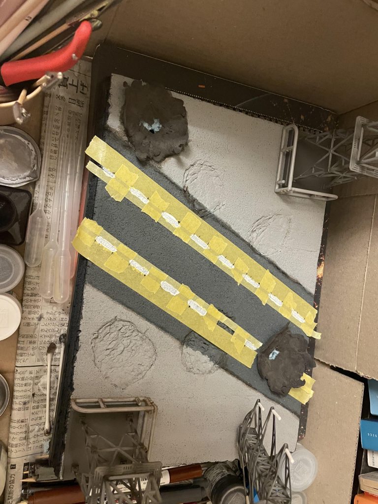 中央の道路に白線を入れたところです。爆発のエフェクトは粘土にピンポン玉(オレンジ)を載せて、赤のLEDで光らせます。その上にコットンを被せるイメージです。ズゴックとゴッグの足の設置面も演出しています。これだけ大きなものがコンクリートに接するので相応の影響はあるのかと。