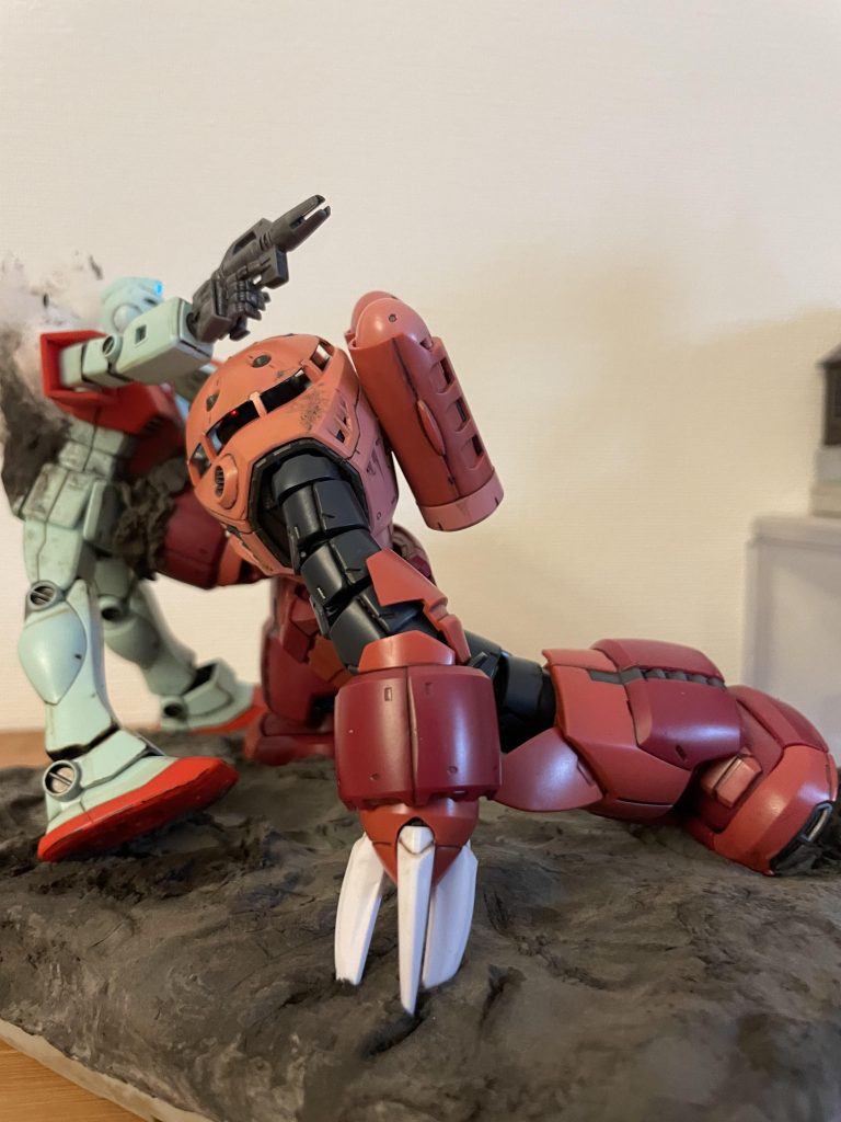 左のクローを地面にめり込ませる事でズゴックの前傾姿勢を維持する工夫をしています。ジムの腹部に大穴を開けるのは忍びなかったので、ROBOT魂シャア専用ズゴックのエフェクトパーツのみをメルカリで購入し、クロー部分を背面に貼り付けて貫通のイメージを演出しています。ベースにダイソーの黒粘土を使用していますが、発色も良く非常に重宝します。