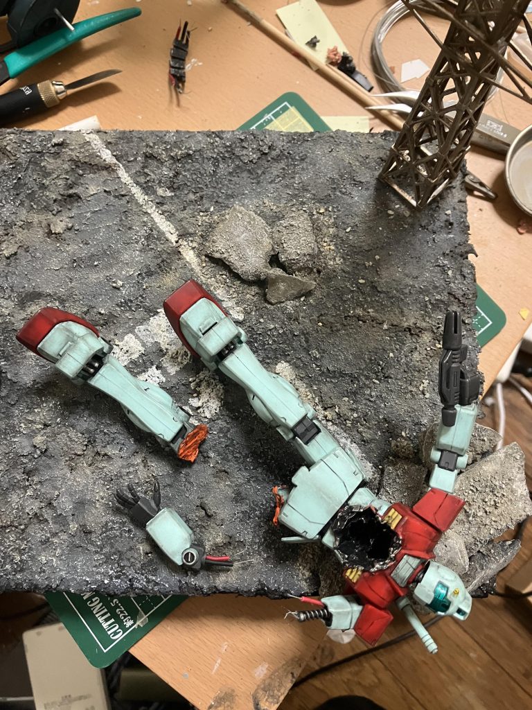 今回はジムのダメージ表現とアスファルトに力を入れてみました💪✨️ジムのダメージ表現、アスファルト共にとてもよく出来たんじゃないかと思います😊まずジムのダメージ表現なのですが、お腹と足ははんだごてを使い、お腹には穴を開け、足は焼き切りました！腕はに二の腕から先をもいだだけなのですが、そのままですとちぎられた感じが出ないので、赤と黒のワイヤーと針金を使い、内部パーツを表現する事で、ちぎられた様に見えるようにしました！！足に関してはズゴックのビームで損傷した感じを出したかったのですが、あんまりビーム痕感が出なかったですね🥲ネットやYouTubeでビーム痕の表現の仕方を調べたのですが、見つからなかったのでどなたかやり方を知っている方、教えていただきたいです、、ちなみにビーム痕の部分は、シタデルカラーのトロールスレイヤーオレンジと言う塗料を使いました！