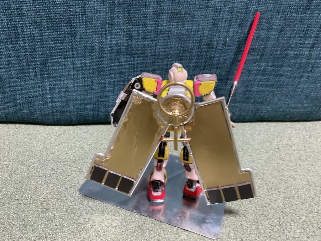 金に塗装した太陽光パネル。そのままでも電気供給できるが、背中から外してその場所で太陽に当て続けワイヤーで電気を送るという事もできる。黒い部分は過剰に生成されたエネルギーを充電、放出する機構でありカリスシステムと呼ばれる。後ろのヴェネスのマークは切り離しの際にミラーより通信を受けたり現在地を示すなどの強力なマグネットシステムであり、アンテナの役割を持つ。