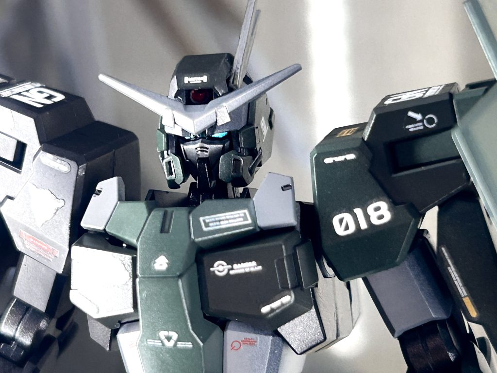 頭部外装はデュナメス、フェイスパーツはケルディムを使用し、ケルディムのアンテナを追加胴体はサバーニャ、四肢にはケルディムを使用全体的なカラーリングはデュナメスサーガを参考にし、ホワイトのパーツはグレーで塗装。型番は3機体の番号を足してGN018にしました。