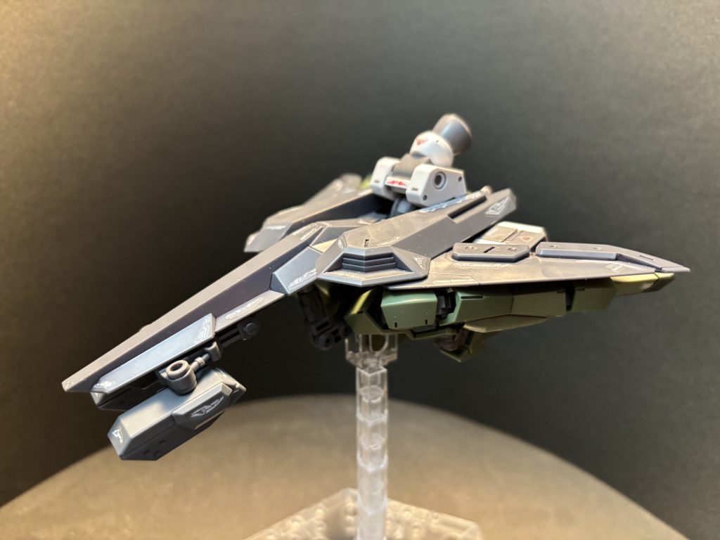 変形シークエンス⑤:ガトリングシールドの持ち手パーツをジョイントパーツと交換し、股関節部分の3mmジョイント穴に接続すれば変形完了です。