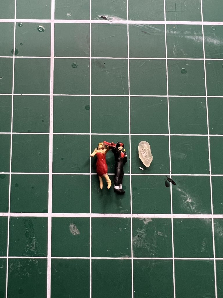 最後にドモンとレインのフィギュア。ビルダーズパーツの1/144 MSフィギュアをポーズ変更のため切って貼ってして形を成形。 鉢巻や肩のアンテナも0.25mmのプラ板を使って作成。 塗装も頑張ってみましたが流石に顔の塗り分けまでは出来ませんでした。サイズ比較用に米粒を置いてみましたが米粒約2個分のサイズ。私にはこの色分けが限界でした(gundam-kao9かなり色々手をくわた