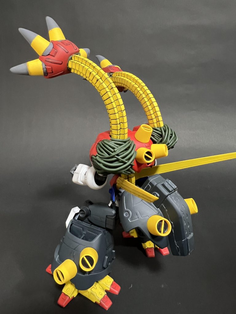 劇中のシーンではデビルガンダムの肩ユニットの後ろ半分が外れて手が出てくるのですがそれを再現する為に肩後ろパーツにパテをもって手のひらや爪の形を成形。空洞になった肩部分はデビルガンダムの再生能力をイメージしてプラ棒を炙り曲げて肩を作成しました。 アーム部は様々な蛇腹状パーツを検討しましたが強度的な問題もありレジンで作成。デビルガンダムのお腹部の蛇腹パーツをパーツ複製して作成しました。なお基部にポリキャップを仕込んではいるので角度を変える程度はできます。(強度の関係上あまりフレキシブルには動かせませんでした)