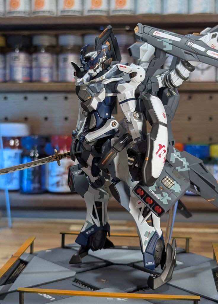 2️⃣ドット迷彩バックパック上下のウイング、脚部のミサイルコンテナ側面、右足内側のヒザ・スネ、左足外側スネに、薄い水色のドット迷彩を入れてみました（両手首にもありますが見えませんね）。もう少し派手に迷彩を入れるべきでしたが、ワンポイントとして見れば謙虚なイメージで収まってます。なお、左側面側からしか見えないよう配置しています（この後の右側面からの写真と比較すると分かりやすいと思います）。3️⃣刃紋日本刀に刃紋塗装を初めてやってみました。まだまだ歪ですけど、それなりにリアルに仕上がったと思います。 