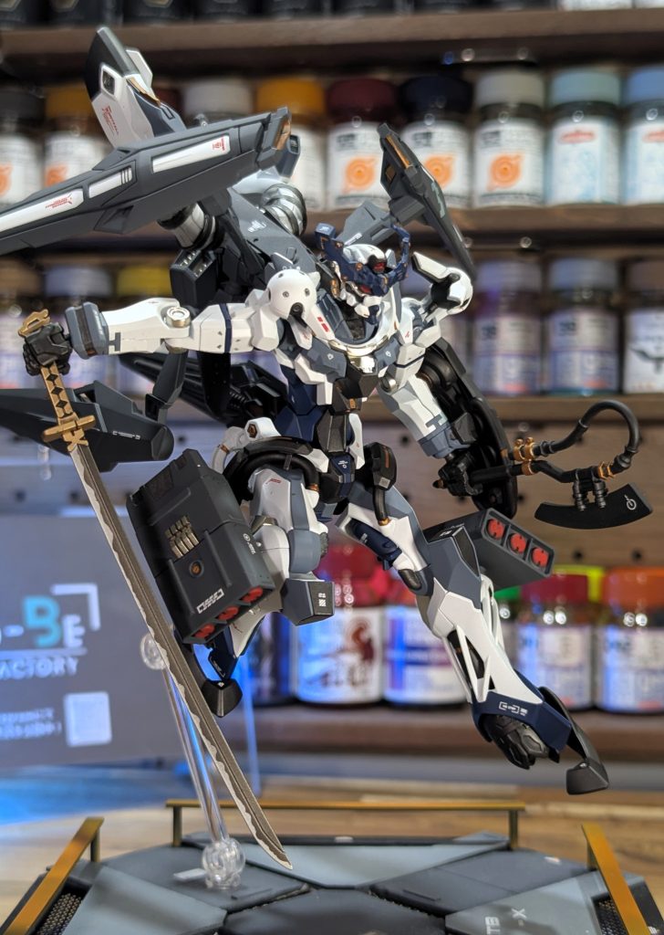 脚部のミサイルコンテナはガンダムオプションパーツを流用。このコンテナ中央部には、３Dプリンターで作成した自作のフィンパーツを取り付けています。日本刀は戦国アストレイから拝借しています。この写真のアングルですとドット迷彩が全く見えず、プレーンな印象に感じるのではないでしょうか？