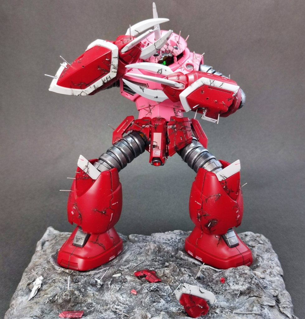 針と例の光、ヒビ割れについてはプライムビデオをコマ送りして確認しなるべく作中に近くなるようにしました。とはいえ例の光を固定するために背面にも針が刺さってたり、コマによってヒビや針も一致してないし追加の傷も足してるので完全一致はしてないのですが、そこそこ近いものができたと思います。爪とズゴック側のアンテナのみ、シアノンとほぼ同じ色だったので肉抜き埋めとシャープ化しました。基本的にはサフレスラッカーですが、ピンクの部分だけ買ったは良いものの死蔵されてた水性ホビーカラーのライブコンサートピンク+αで塗装してます。 手甲などの脱落部分や断面部分は抉ったときの白化とかが良い感じだったので、一旦全部塗った後、薄め液で落としました。左手の手甲はコマ送りすると脱落部分が3分割されてましたが、元パーツ分かりやすくするためにあえて大きめに残して岩場に落としてます