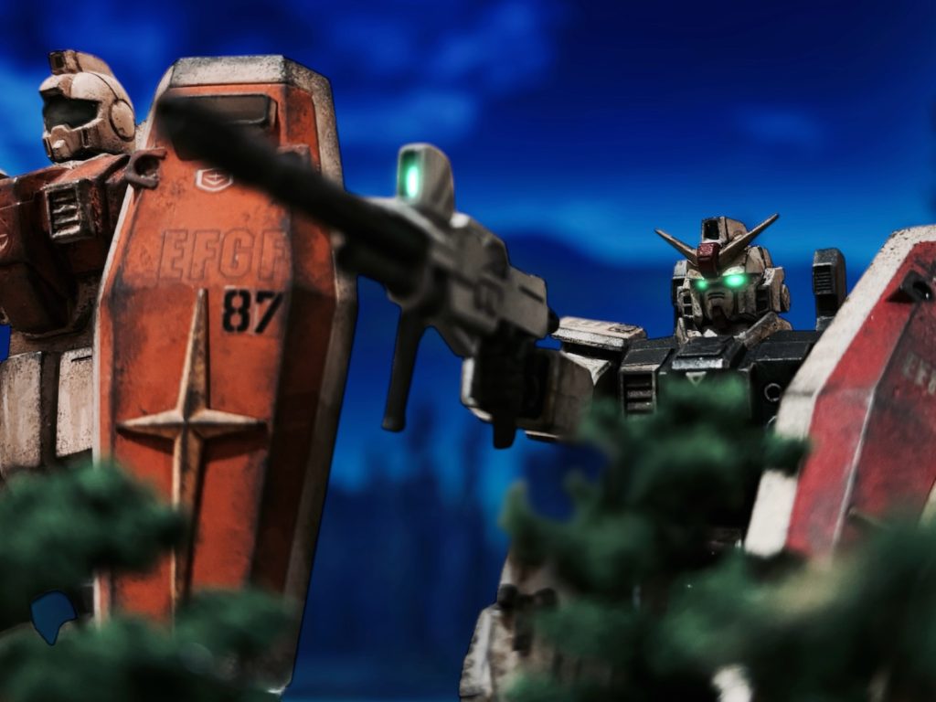 「MSが稼働している……ザクに、グフ。」サイトスコープ越しに見える基地では、2機のMSが露天駐機されている。モノアイにかすかな光が見える。火は入っているらしい。『2機だけか?』イギーの問いには、ホバートラックのマークが答える。『ソナーの感じも、2機でしょうね。ザクとグフ、間違い無いですよ。』「まずザクを狙うぞ。グフなら気づかれても、近づいてくるところを狙撃できる。」『そのときは俺に取っ組み合わせろ。前に出るからな。』息巻くイギーに、頼んだと告げ、ヘントは照準を絞る。歩兵隊と戦車隊は、予定通り展開しているだろうか。