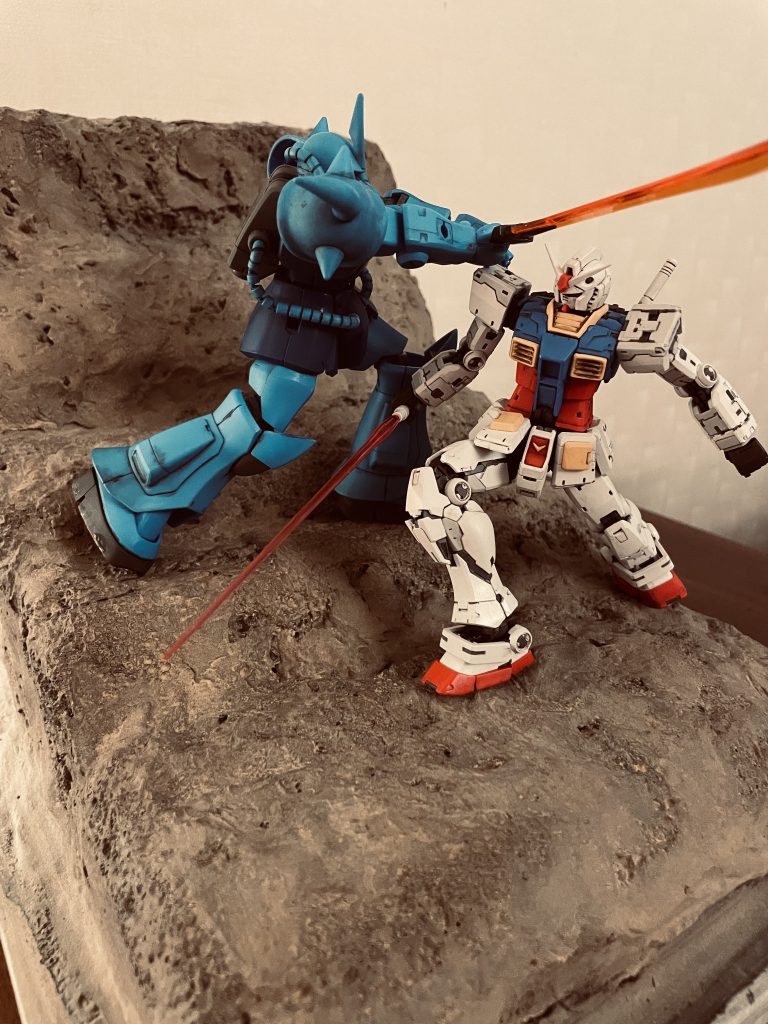 左後方より。グフのサイド腰アーマーは足の動きに干渉するので一度切り離し大腿部の動きに連動するようにしています。構図上グフの左足は大きく前に踏ん張る必要があったのでこのような処理をしております。 