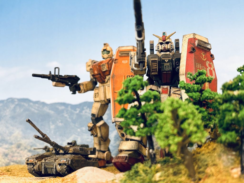 木立の中に、MS大のダミーバルーンがむくむくと立ち上がる。その距離、訳10km。「最大望遠で10kmか……」ガンダムのビームライフルでダミーバルーンに標準を定めながら、ヘントは呟く。『我々には当てんでくださいよ。』ホバートラックからの通信には、マークの軽口だ。「場所も距離も違いすぎる、そこまでポンコツじゃないよ。」 ビームライフルの、最大望遠での狙撃訓練である。隊に与えられた初めての実戦を伴う作戦行動は、穀倉地帯にある敵拠点への夜襲である。夜闇に紛れて南から敵地に近づき、ガンダムのビームライフルで、敵守備隊のMSを狙撃する。混乱に乗じて、北から迂回した戦車隊と歩兵隊とで、拠点を制圧する。末端の小規模拠点で、軍事的価値は高くないが、一応敵の糧秣基地であるため、多少の打撃は与えられる。何よりMSの稼働データが欲しいのだろう。オデッサディを前に、各地で小規模な小競り合いが頻発していた。 その、作戦開始前に、こうして何度か狙撃訓練を行っている。『おー、今日も盛大に外したな。』イギーが通信機越しに茶化す。訓練におけるヘントの集弾率は、あまり良くなかった。