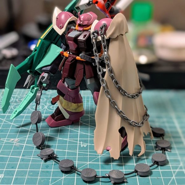 アーティファクトで中断していた我が小隊員のMS制作ですが、ちょっとだけすすめました！某闇市で手に入れたチェーンマインと左肩にもチェーンを付けました🤤なんか一気に厨二臭くなったな、いいぞ～😎✨チェーンマインはなんとかマント内に収納させたいけどまだ考え中です🤔 あとスナイパー機ですが、先月プレバンで購入したハイザックカスタムを水星の魔女のある機体とミキシングしてサイコミュ的な機体に仕上げるつもりです😋💡（1枚目）