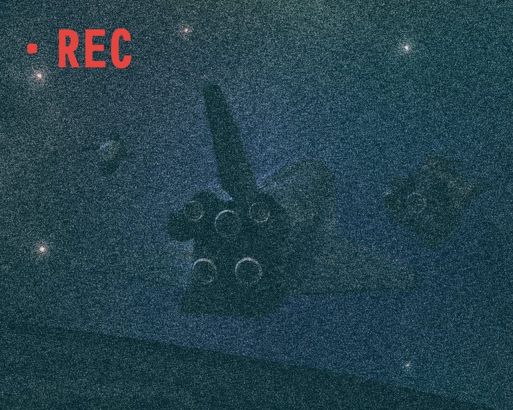 「こりゃマズイかな…？」ノイズは多いが映像には中型のシャトルの後ろ姿と、2つの影が見えた。地球から来た友軍だろうか。いや、救難信号は発していない。これだけでは判断できないとハイトはモアへ通信する。「こちらセンリガン00、トライバル・リーダー、ウォーリア01取れますか？」「こちらウォーリア01、どうした？」「地球裏側に中型のシャトルらしき機影と何か小型艇の様な影があります。ただ所属が分からず隊長に判断を願いたいのです」「中型シャトルだと？映像を回せるか？」友軍が上がってきたなら大半は小型のHLVや大気圏離脱能力のあるザンジバル級の筈だ。しかし敵機を鹵獲した可能性もある。「リアルタイムレーザー通信で回します」モアにドローン映像を送ると暫しの間が開く。モアは送らてきた映像を見た。(あれは我が軍のものではない…。その周りにいるのは連邦軍の無人哨戒艇ではないだろうか)モアは以前自分達が遭遇した無人機とデータ照合をすると直ぐに答えがでた。「照合率100%、連邦軍機か…」救難信号も出さず、明かりを落とし息を潜めるようにいるという事は、鹵獲でなく敵である可能性が高い。「センリガン00聞こえるか?」「どうぞ」「そいつは連邦軍の可能性が高い。不用意に近づくなよ」「了解、自分はどうしますか？」「そのままそのシャトルを監視。何か動きがあれば直ぐに俺に教えろ」「了解しました」まだ相手はハイトの存在に気づいていない様子だ。しかし、シャトルの護衛に着いているのがあの哨戒艇であれば、あちらも目と耳は良い筈である。(……輸送機か、一体何を積んでいるんだ？)モアはその輸送機の積荷が気になったが、今は下手に仕掛けて交戦するのは避けたい所が本音だ。するとモアのドム試作実験機にノアズ・アークから通信が入る。「こちらウォーリア01、ノアズ・アークどうした?」