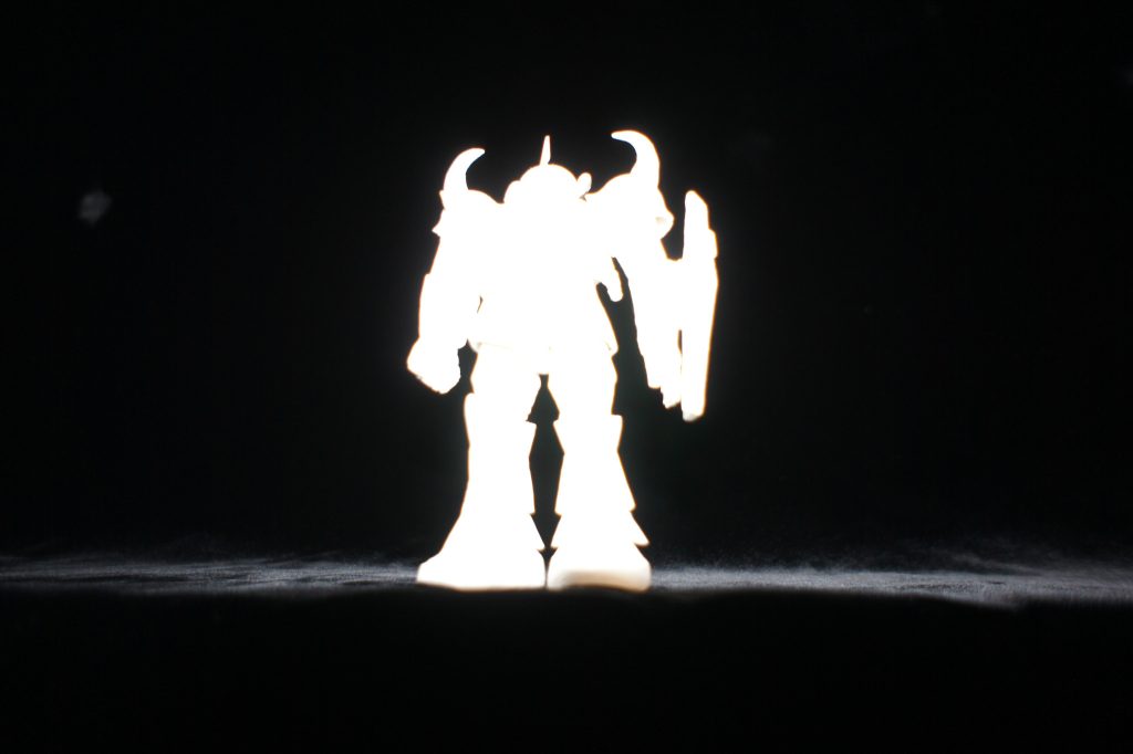 おまけ。間違えてフラッシュを有効にして撮ったら何とも神々しい写真が撮れました。「いいね」、を押していただけると、きっとご利益があります(gundam-kao2)。それにしても、グフのシルエットはカッコいいですね!次回の投稿は1/1200ホワイトベースの予定です。グフはその後にできればいいな、と思っています。