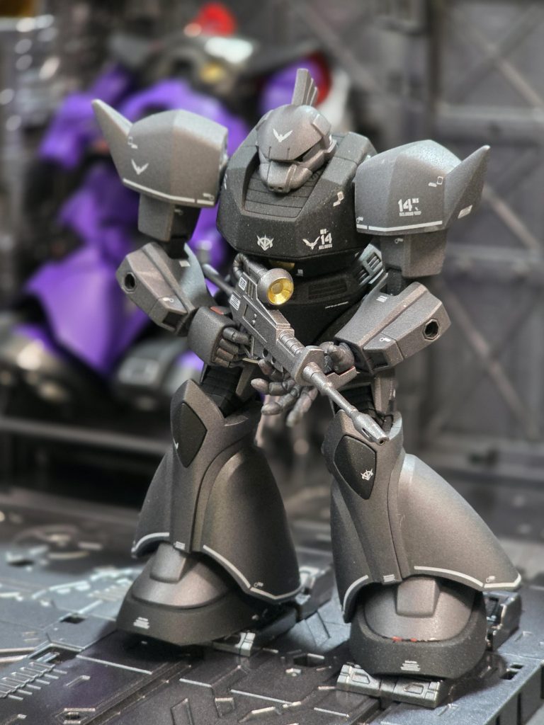 ベースキットはシャア専用ゲルググで、パーツ構成は前に製作したリック・ドムとほぼ一緒。成型色の赤・オレンジ系から黒系にするため下地にブラックサフを吹き、ボディはマットブラック、手足・頭部・関節はガンメタをタミヤスプレーで。コクピットだけワンポイントのゴールドをマーカー塗り。デカールは海外モノを流用して最後につや消しトップコートを2回ほど吹いてマット感を強調。でもちょっと粉ふいたみたいになってしまったため、ベースがマットの時には半光沢のほうが良かったのかもと反省。ビームライフルはライトガンメタにしてボディ色との差別化を。例のディスプレイベースシリーズにカタパルトが追加された?らしいので早速採用。後方MSハンガーには息子製作リック・ドムが見切れ友情出演。