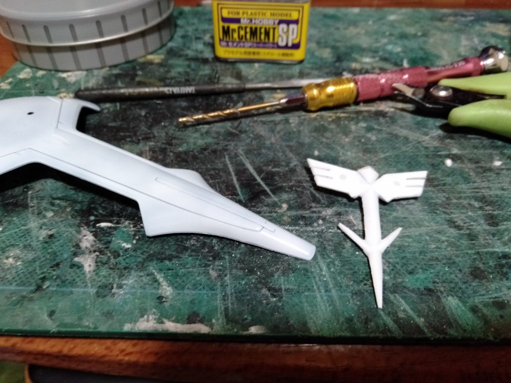 デカールで再現されてる”ネオジオン”国章です、俺はサザビーは必ずデカールからプラバン積層からの削り出しで、モールドを製作してます。 今回も漏れず、製作し立体的になるようにC面を付けるようにします、まぁ不出来と想わずにあくまで単なる”見栄え”のパーツと。w シールド表面に2.1mmの穴を開口し、モールドにも同じく開口して接続に2mmのプラ棒を接着して、乾燥後に表面を整形してます。コレで塗装後に張り付けます。 写真には入っていませんが同じく、フロント左スカートにある”シャア・アズナブル”マーク(音符に見えるやつ)も製作していました。