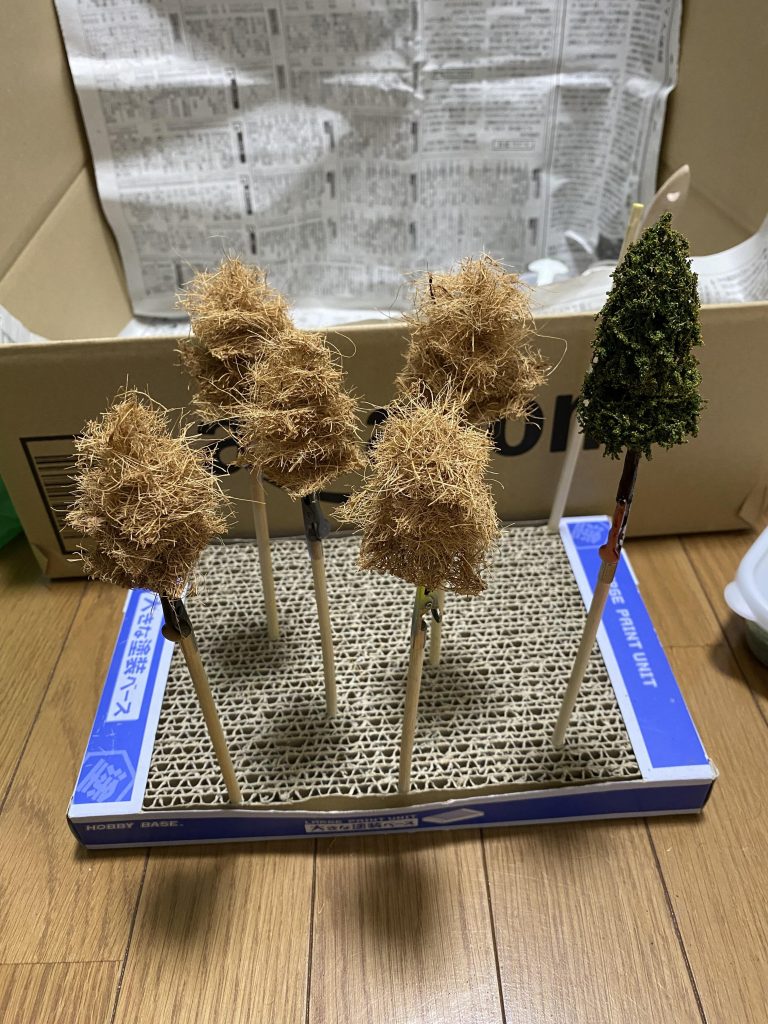 ヤシマットを剥がして爪楊枝に刺し、ジオラマ用の粉を2色程ふりかけました。幹は割り箸を茶系の絵の具で塗って、ウォールナットニスでコート。