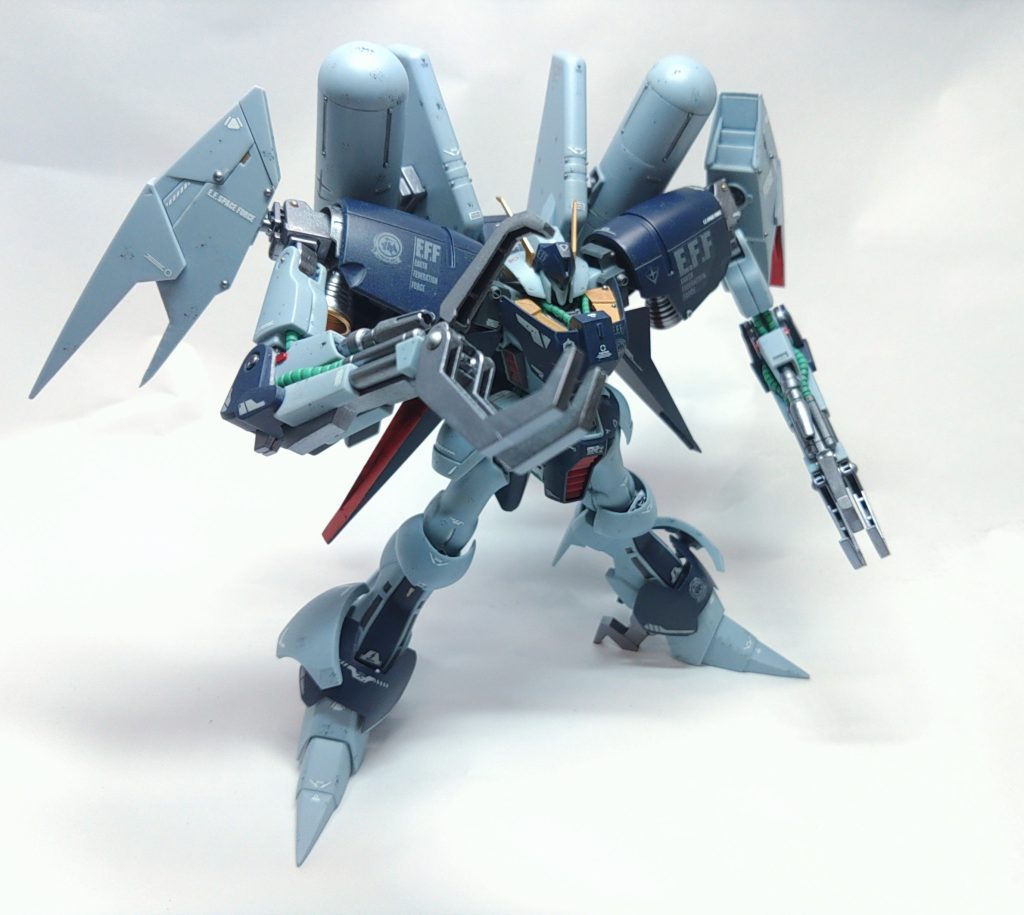 成型色仕上げを重点におきつつ、ボリューム過多の上半身のバランスを、塊感をとるように各パーツのバランスを調整していきます。製作途中に改造部の写真を少し載せています。改造点は以下です。↓頭頬のガードの厚みを外側から半分ぐらい削って薄くする。アゴ下を削り込んでマスク部を短くする。カメラ内のデュエルアイのモールドを削り込んでハッキリさせる。 胴両肩付け根に、バイアラン余剰パーツ(プロペラントタンクとバーニアの接続部のグレーのパーツ)を加工して肩幅を広くする。胸部装甲左右の曲がるっている部分に裏から切れ目を入れて押し広げてから瞬間接着剤で固定して大型化+取り付け位置にランナータグを2枚ほど挟んで2ミリほど上に調整する。バックパック接続部を切り抜いて、空いた部分にランナータグを貼り付けてバックパックの接続位置を上方にずらす。脇のサイドスラスターにランナータグを貼って延長 腕クローの先端部の曲がった部分から切り離して、バイアラン余剰パーツのクローの先端を大き目に切り出して接着して大型化肩内のバーニアに、バイアラン余剰パーツのプロペラントタンクのバーニアを低く削ったものを下駄として足してから従来のバーニアを再接着正面からでもバーニアが見えるように改造。足足首アーマーのサイドガードが設定画だとキットよりも傾いているので、バイアラン余剰パーツの足首サイドガードの接続部を切り出して内側に貼り付けて角度を変更。 プロペラントタンクやや上にせりだすとシルエットに影響してカッコいいのではないか?と改造付け根を下げると相対的にプロペラントタンクが上にせりだすので、パイプカッターでプロペラントタンクの上下の筋彫り位置付近からパイプカッターで3分割、まん中の接続部を含むパーツを上下の反転して再接着