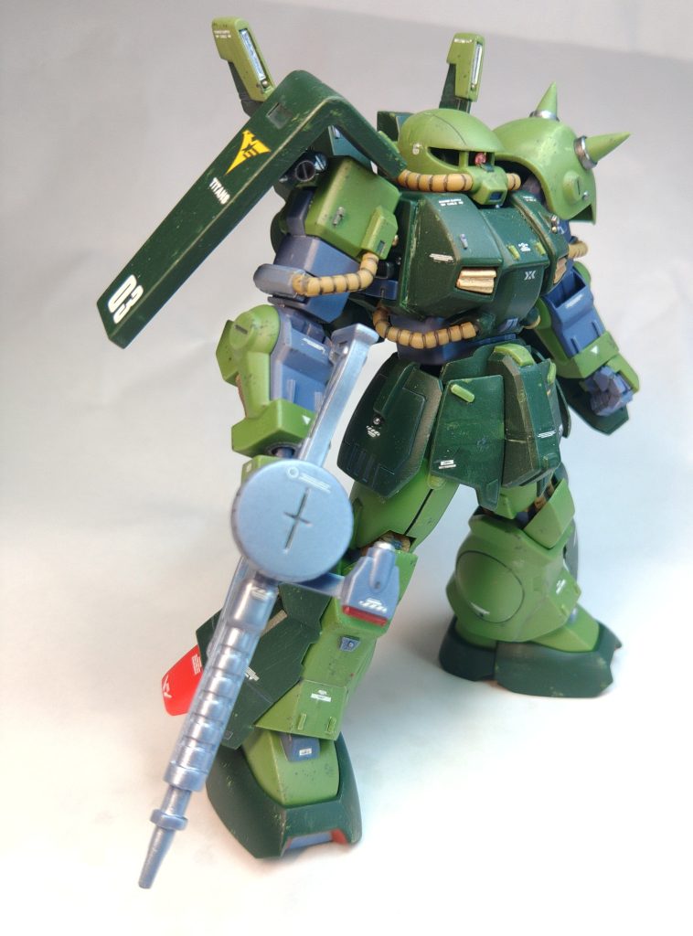 成型色仕上げですが、キットの構成は把握しているつもりなので、あまり気にせずにパーツを切り刻んでいます。改造点は以下です↓頭部ヘルメットをそのままに、モノアイ部で切り離して目付きを悪くするために幅詰めして再接着。その際、左右の分割面でそれぞれ0,5ミリほど削って、フェイス部で計1ミリほど幅詰めしています。ヘルメット部もその際、前後に切断してランナータグを挟んで2ミリほど延長しています。ヘルメットごと幅詰めすると頭頂部の丸みが減ってゴリラのようになるので(ザク3で失敗済み)再接着後に調整しています。モノアイは下面をくり貫いて、下から3ミリピンバイスで空けた穴にプラ棒を通したものにエイチアイズを貼って無理矢理可動にしています。鼻先の濃い緑のパーツはランナータグです。 胴部中心のコクピット部、左右それぞれのダクトブロックで三分割して、中心のコクピットブロックを台形に削ってから再接着。 これによって上に向かって胴が狭まる、ザクの肩ハの字切りと同じ効果があり、小型化した頭とのバランスが取れる。肩の付け根を3ミリほど上にずらし、やや後ろに傾くように再接着。これで怒り肩になります。腰アーマーは中央前部をまん中で切断してランナータグを挟み2ミリ延長。フロントアーマーも中央で切り離してランナータグを挟み3ミリ延長。リアアーマーは垂直すぎたので、切り離してランナータグを挟んで角度を着けて再接着。 腕部肩のシールドは付け根の位置を上方、中心よりやや後ろに修正。これによって稼働範囲が増えます。スパイクアーマーはスパイクを切り離してシャープ化して再接着、ついでにランナーパテを盛ってアーマー部にエッジを追加しています。色味が変わってしまったのは反省点。左手首は親指とその他指を切り離して、ランナータグで手の内側の甲を作ってから再接着。 脚部足首の靴?の部分と足首で別パーツになっているので、そこを左右それぞれ内側に傾くように接着。これによって設置性が向上する。ヒザのパイプパーツを片方反対に着けてしまったが、修正不能になってしまったのは反省点。 バックパック取り付け位置の穴を3ミリほどしたに空け直す。これで相対的にバックパックの取り付け位置が上がる。左右に張り出したセンサー部はどのみち塗装しなければならないので、5ミリプラ板で囲ってセンサー部を復元。ラピーテープを貼った透明プラ板をセンサーに貼り付けた。