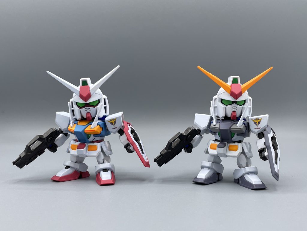 2ショット キット的な話をすると、SDとして発売されているのは左のカラフルな実戦配備型の方だけです。右のグレートーンのOガンダムは、私が塗り替えたものです。隠ぺい力の高いグレー系の塗装なので、比較的塗装しやすいキットであると言えると思います。 SDなので2機分買ってもお安いですし、比較的いつでも棚から私たちを見守ってくれておりますので・・・(笑) 低価格帯のキットであるにも関わらず、一通りの武装やド派手なGNフェザーが付属するなど、プレイバリューの高いキットになっています。