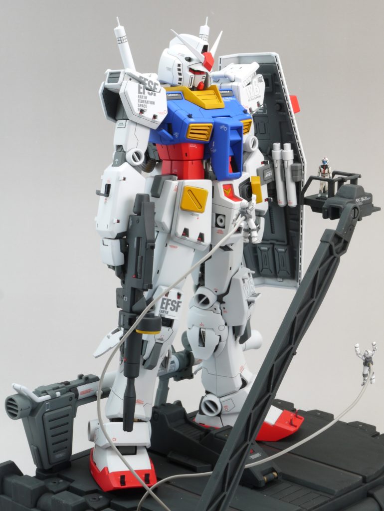 カタパルトは改造後に部分塗装し、水転写式デカールを貼り付け、ツヤ消しトップコートをしてからウェザリングカラーで汚し、再度ツヤ消しトップコートで仕上げました。ハの字に開けなくなるので、足を載せる部分はカットしました。後端にはバズーカの置台を設置してあります。本体のオシリにも取り付けられるはずですが、シールドと干渉するのでこちらに置くことを推奨します。パイロットは部分塗装し、安定して立つように台座をつくって接着し、ツヤ消しトップコートをしています。クルーはMk-Ⅱのものを同様に仕上げています。