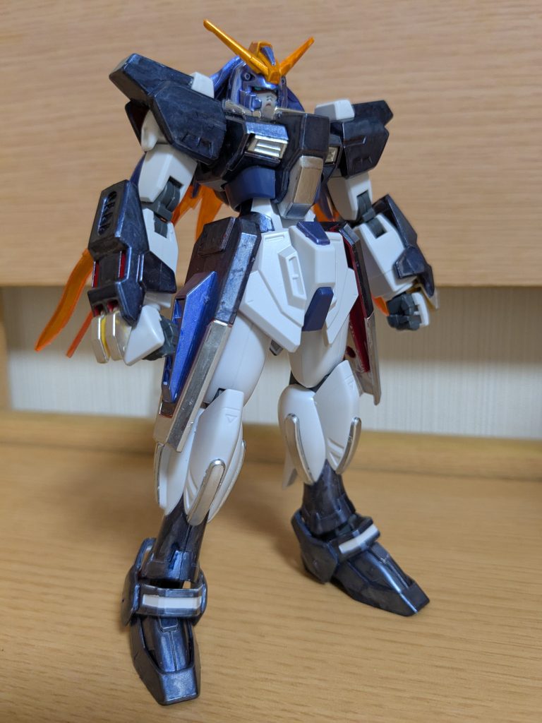 素立ちで１枚。色レシピを上から順に確認です。頭は彼女の髪をイメージしてメタリックバイオレット、アンテナは三度笠や髪の一部をイメージしてメタリックオレンジです。体、肩、腕装甲は彼女の上着をイメージしてメタリックダークブルー、その下に着たワンピースをイメージして、黄色の部分や首回りをシャインシルバー。腰はサイドスカートをシールドに付け替え、メインをメタリックダークブルー、先端をシャインシルバー。腰紐をイメージしてサイドスカートのダクト部分と腰中央のポイントをメタリックバイオレットにしました。足はスネから下をメタリックダークブルーにしてブーツのイメージにしてみました。クリアブルーのエフェクト部分はすべてシャインシルバーで塗装です。