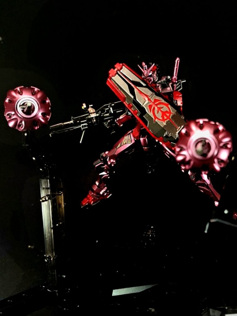 シールド腕部にエクステンダーを介してマウントされる、腕部を覆い隠すことができるほどの大型シールド。表面にはジオン公国の国章が描かれていたが、シュウジ搭乗時には経年劣化によって掠れてしまっている。バイナリーズとのクランバトルでヒート・サーベルを防ぐ際に破壊された。