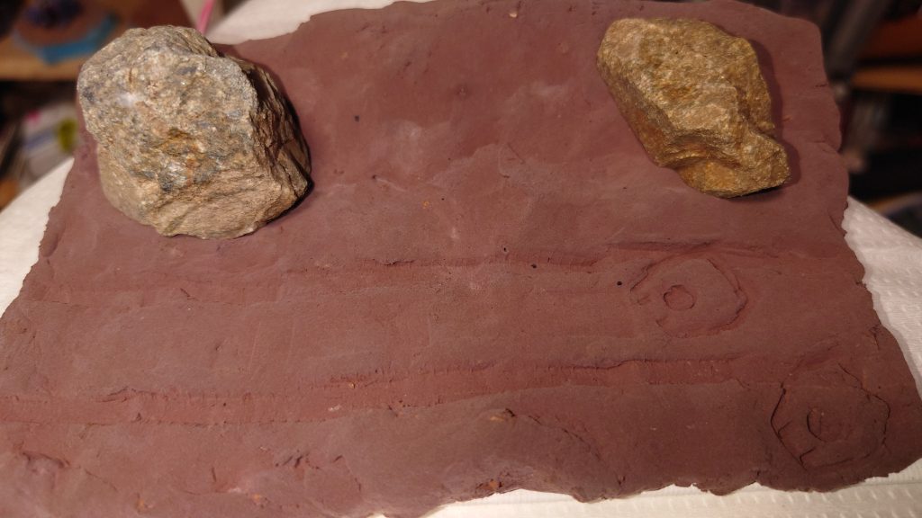 台座は、葉書よりやや大きめのキャンバスパネル 百均です 木工用ボンドを水に溶かして塗りつけ、粘土を貼り付け、拾った石を配置 手前は平らにして道、奥は盛り上がってます マゼラアタックのキャタピラ押し付けて轍にしました 右端にザクⅡの足跡も付けました